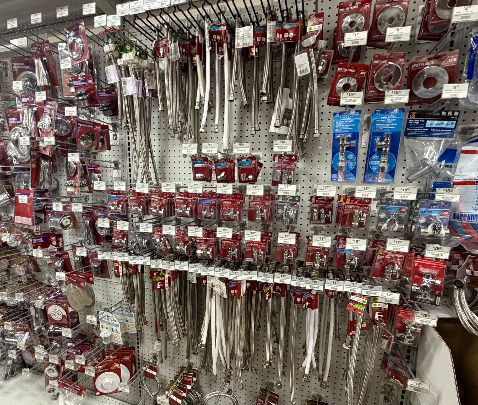 Shelves stocked with Ace brand plumbing supply lines, valves, and split flanges at Hessler Paint & Hardware in Delray Beach, Florida.