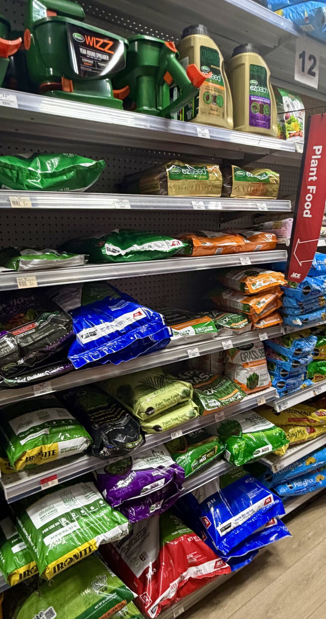 Shelves of Scotts Wizz spreaders, EZ Seed, and various bags of grass seed and plant food at Hessler Paint & Hardware in Delray Beach, Florida.