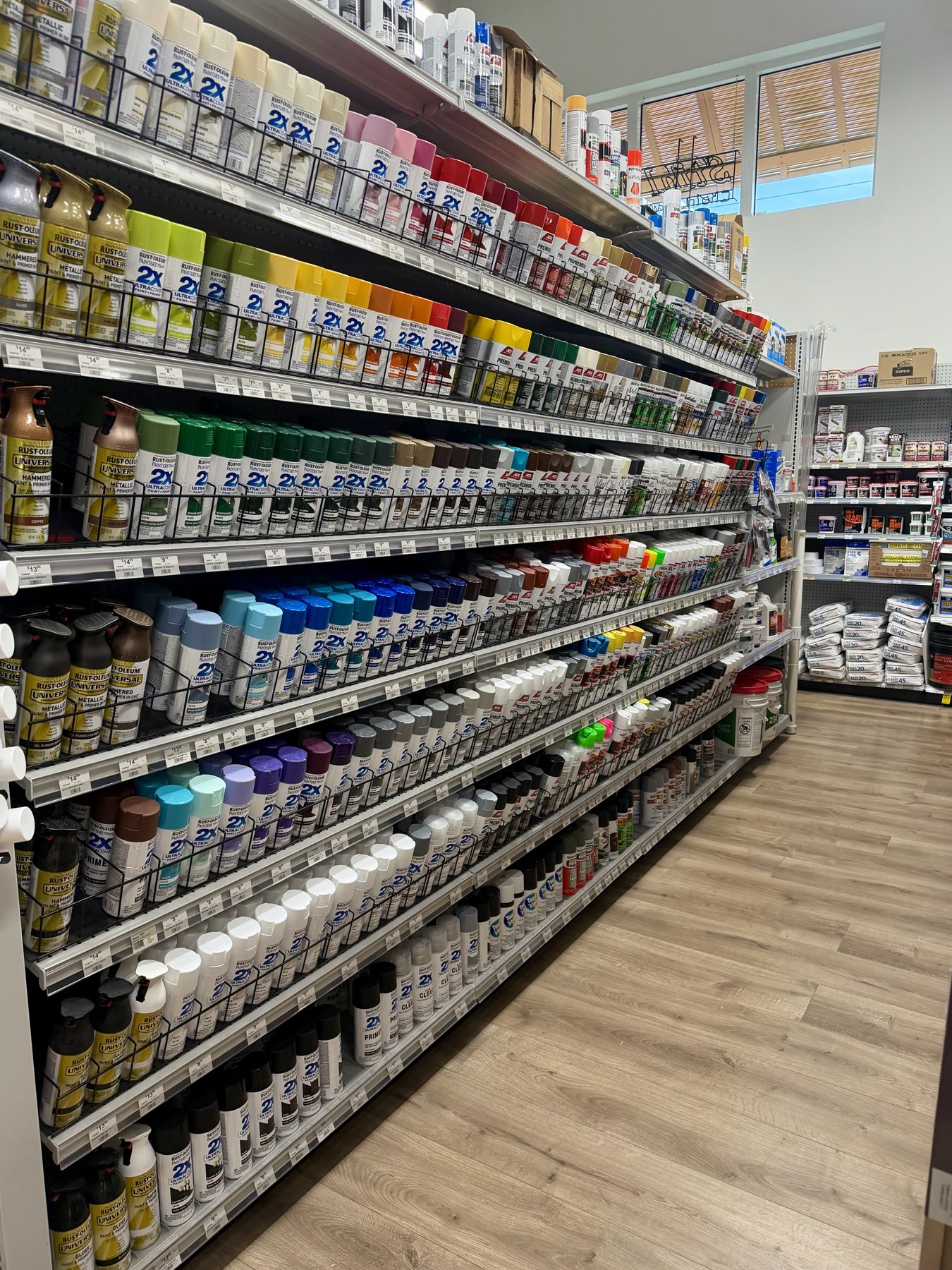 Shelves filled with Rust-Oleum Painter's Touch 2X Ultra Cover and Universal aerosol spray paint cans in various colors at Hessler Paint & Hardware in Delray Beach, Florida.