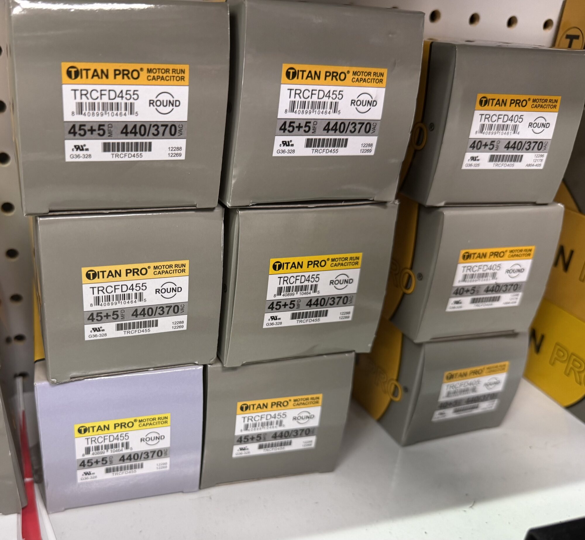 Titan Pro motor run capacitors including TRCFD455 and TRCFD405 models on a store shelf at Hessler Paint & Hardware in Delray Beach, Florida.