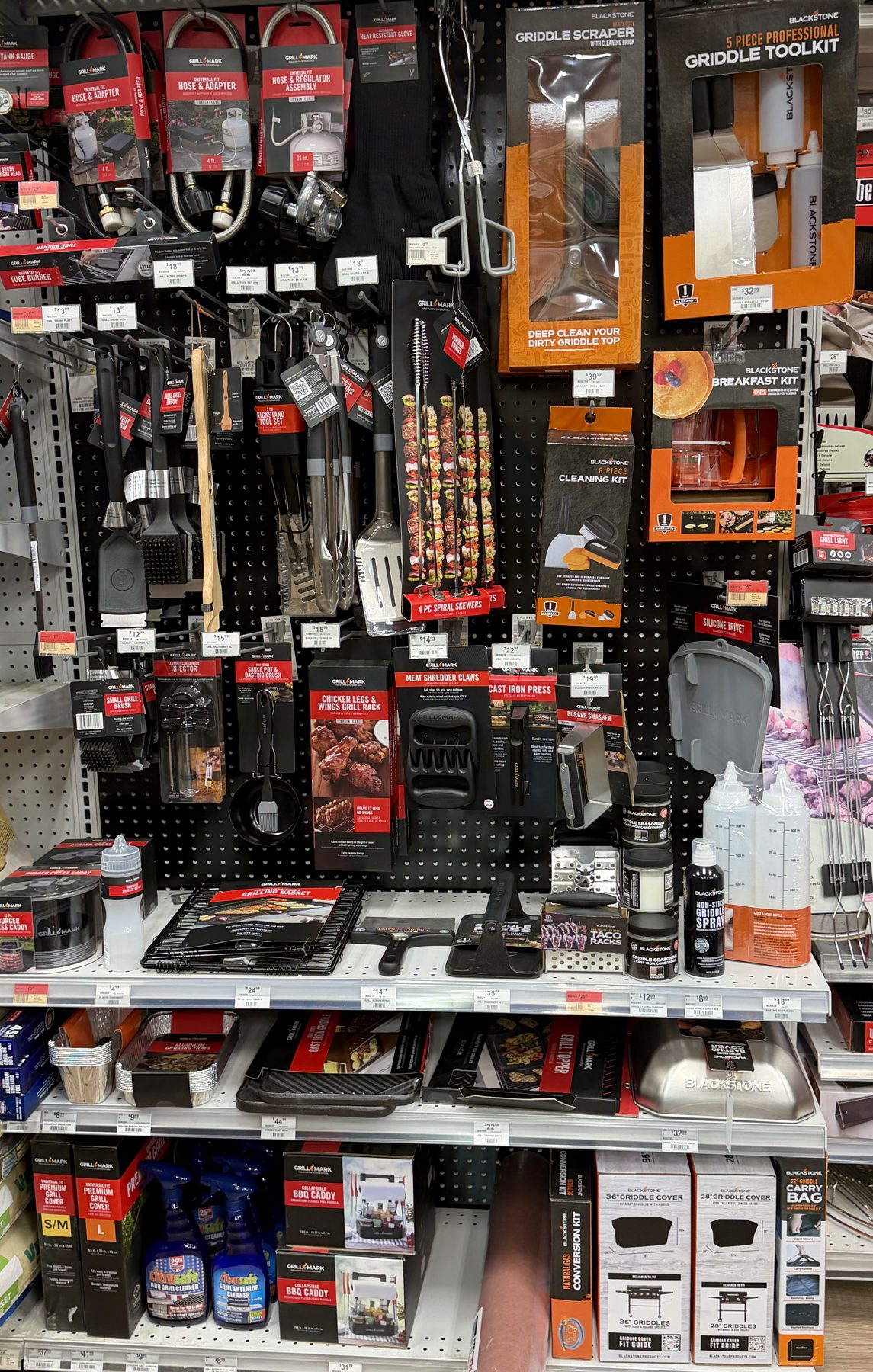 Display wall of Blackstone and Grill Mark BBQ tools, griddle toolkits, scrapers, skewers, and cleaning supplies at Hessler Paint & Hardware in Delray Beach, Florida.
