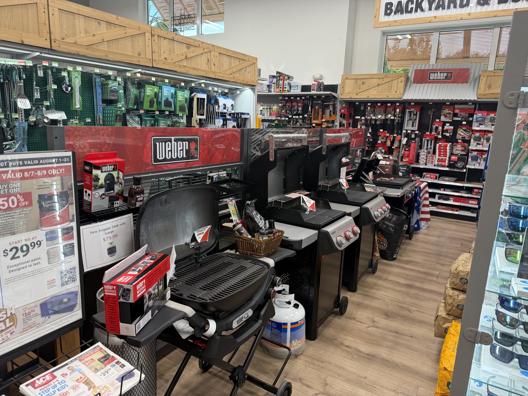 Weber portable and gas grills on display alongside grilling accessories and charcoal at Hessler Paint & Hardware in Delray Beach, Florida.