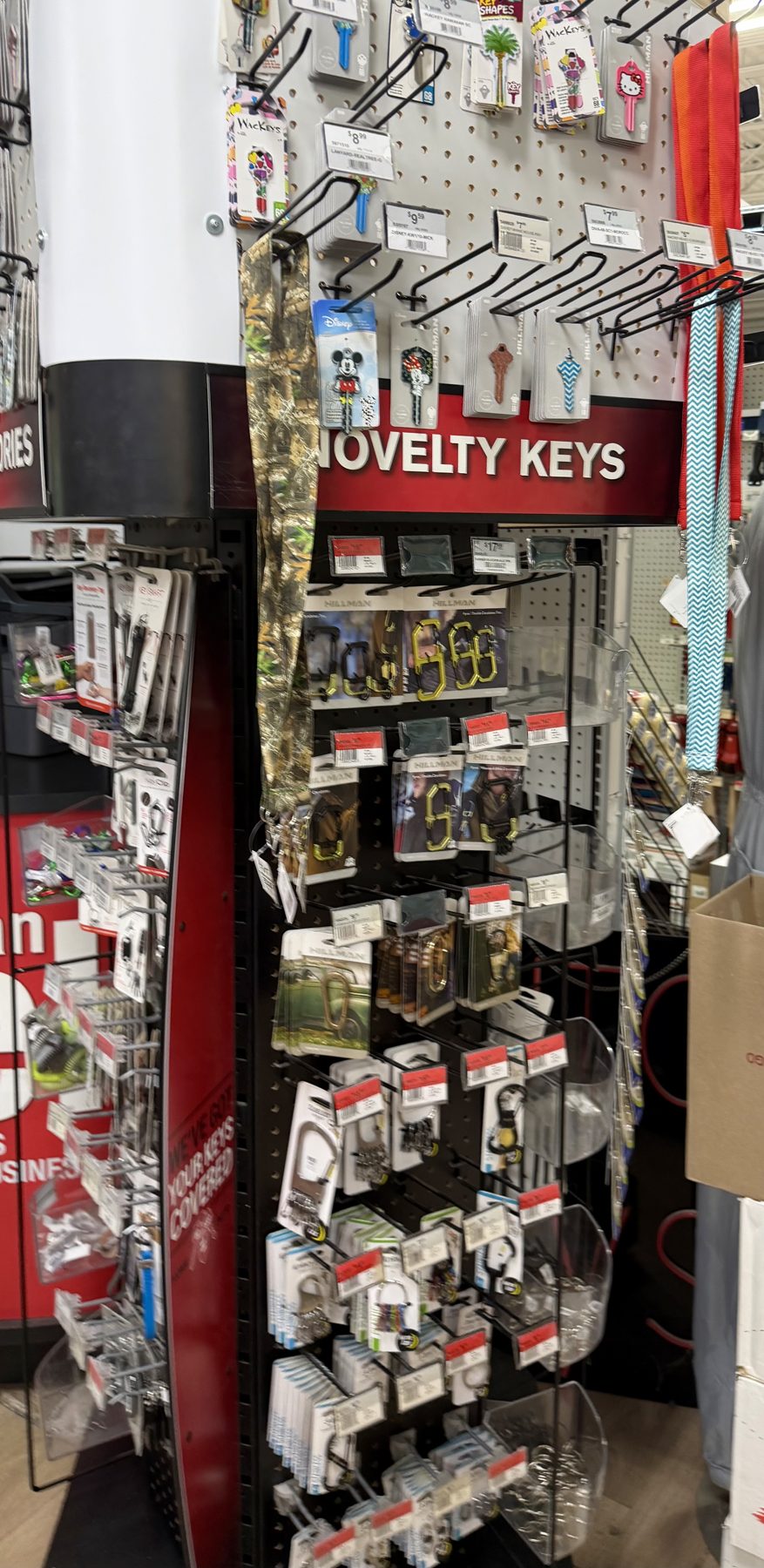 Novelty key blanks display rack featuring Disney characters, colorful keychains, lanyards, and Hillman key accessories at Hessler Paint & Hardware in Delray Beach, Florida.