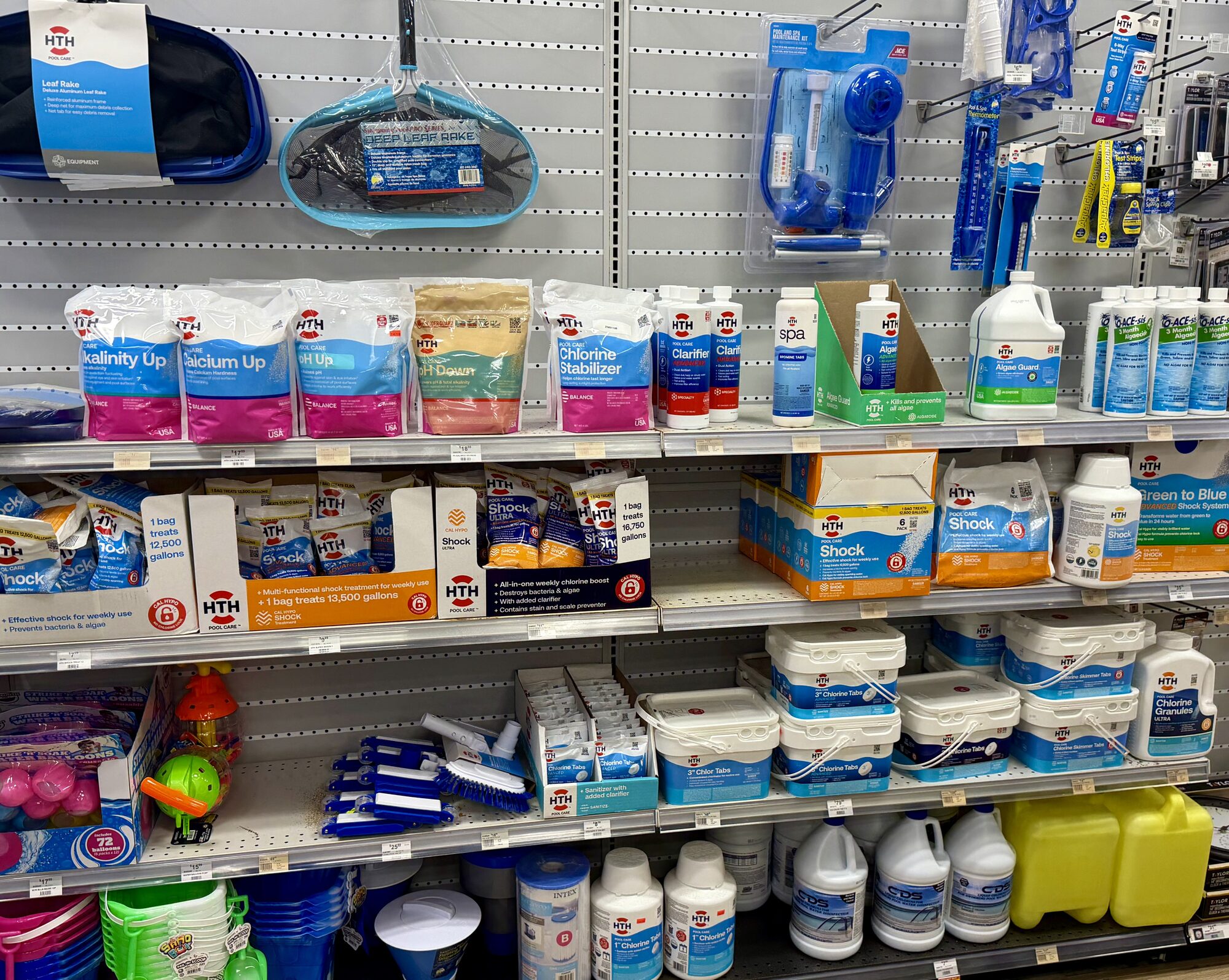 HTH pool care chemicals, chlorine tablets, shock, leaf rakes, and water balancers on store shelves at Hessler Paint & Hardware in Delray Beach, Florida.