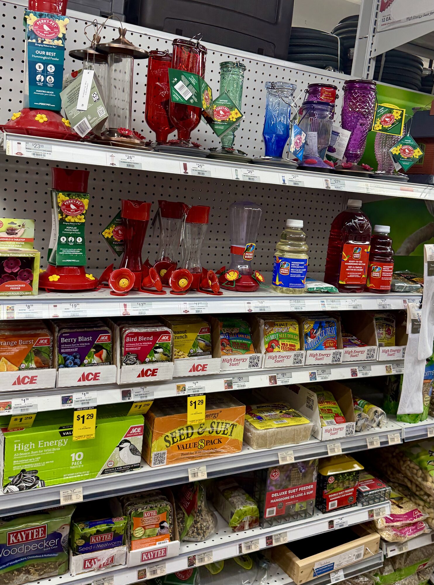 A variety of Perky-Pet bird feeders, Ace Hardware bird seed, and Kaytee suet cakes on store shelves at Hessler Paint & Hardware in Delray Beach, Florida.