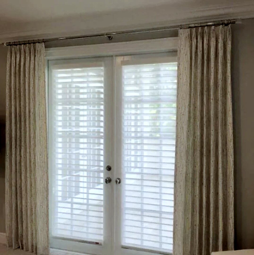 Pinch pleat drapery panels on a chrome rod flanking a pair of French doors