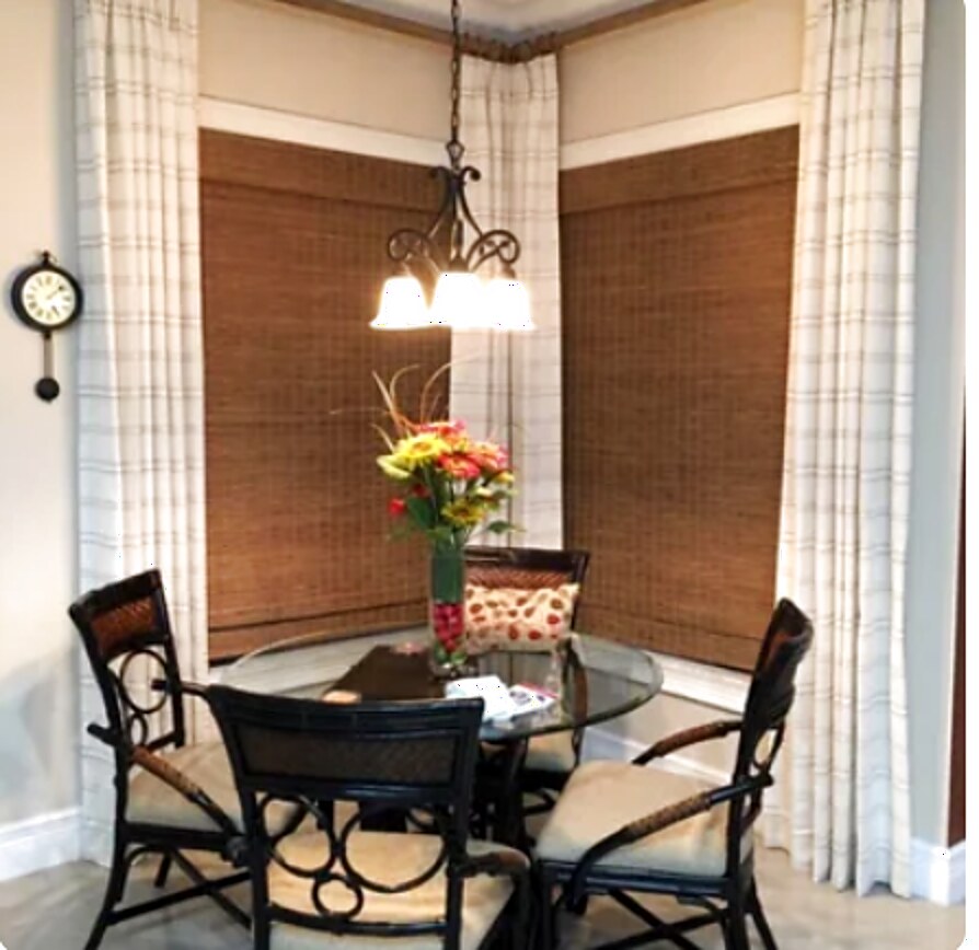 Plaid drapery panels framing a breakfast nook with woven wood shades behind