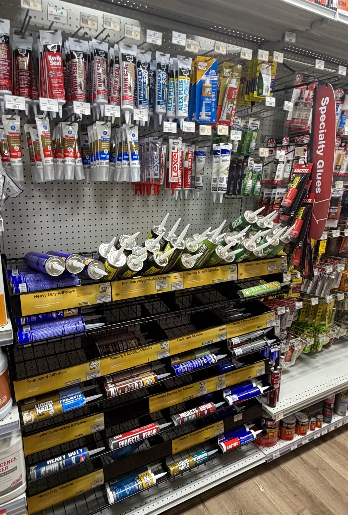 Selection of caulks, sealants, construction adhesives, and specialty glues from DAP, Liquid Nails, GE, Lexel, and Loctite displayed on shelves at Hessler Paint & Hardware in Delray Beach, Florida.