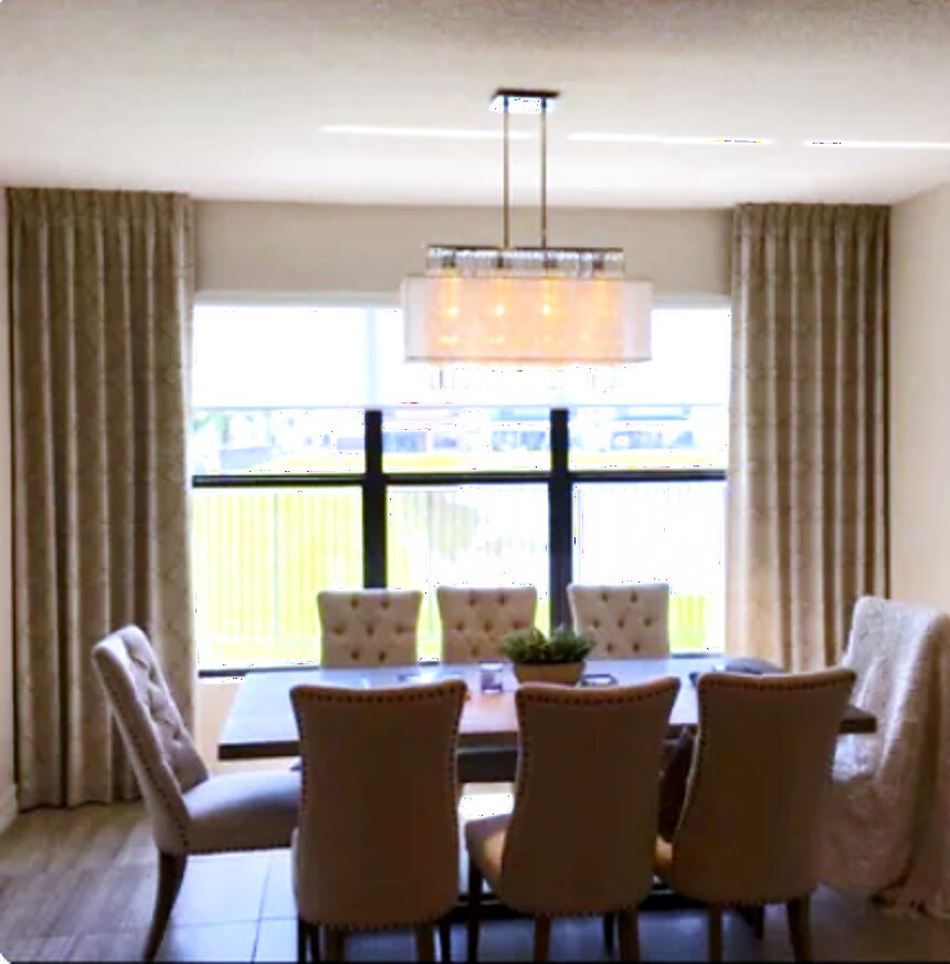 Full-length linen drapery panels stacked off the glass in a dining room