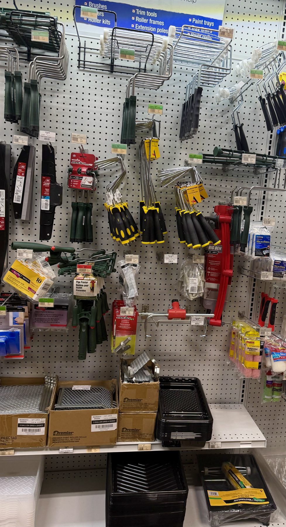 A pegboard wall display filled with paint roller frames, specialty painting tools, paint trays, and roller grid inserts at Hessler Paint & Hardware in Delray Beach, Florida.