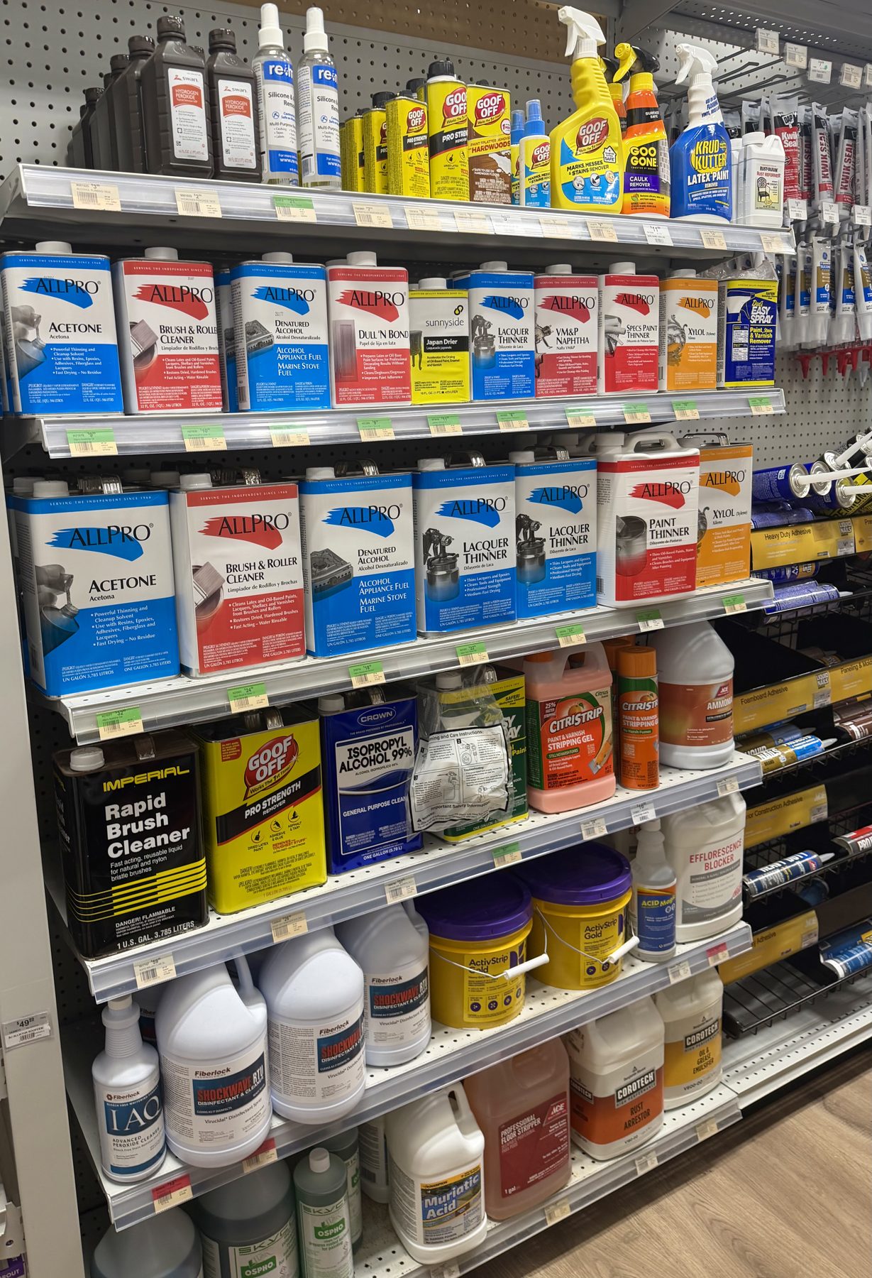 Aisle shelves fully stocked with paint solvents, acetone, lacquer thinners, and brush cleaners from brands like AllPro, Goof Off, Citristrip, and Sunnyside at Hessler Paint & Hardware in Delray Beach, Florida.