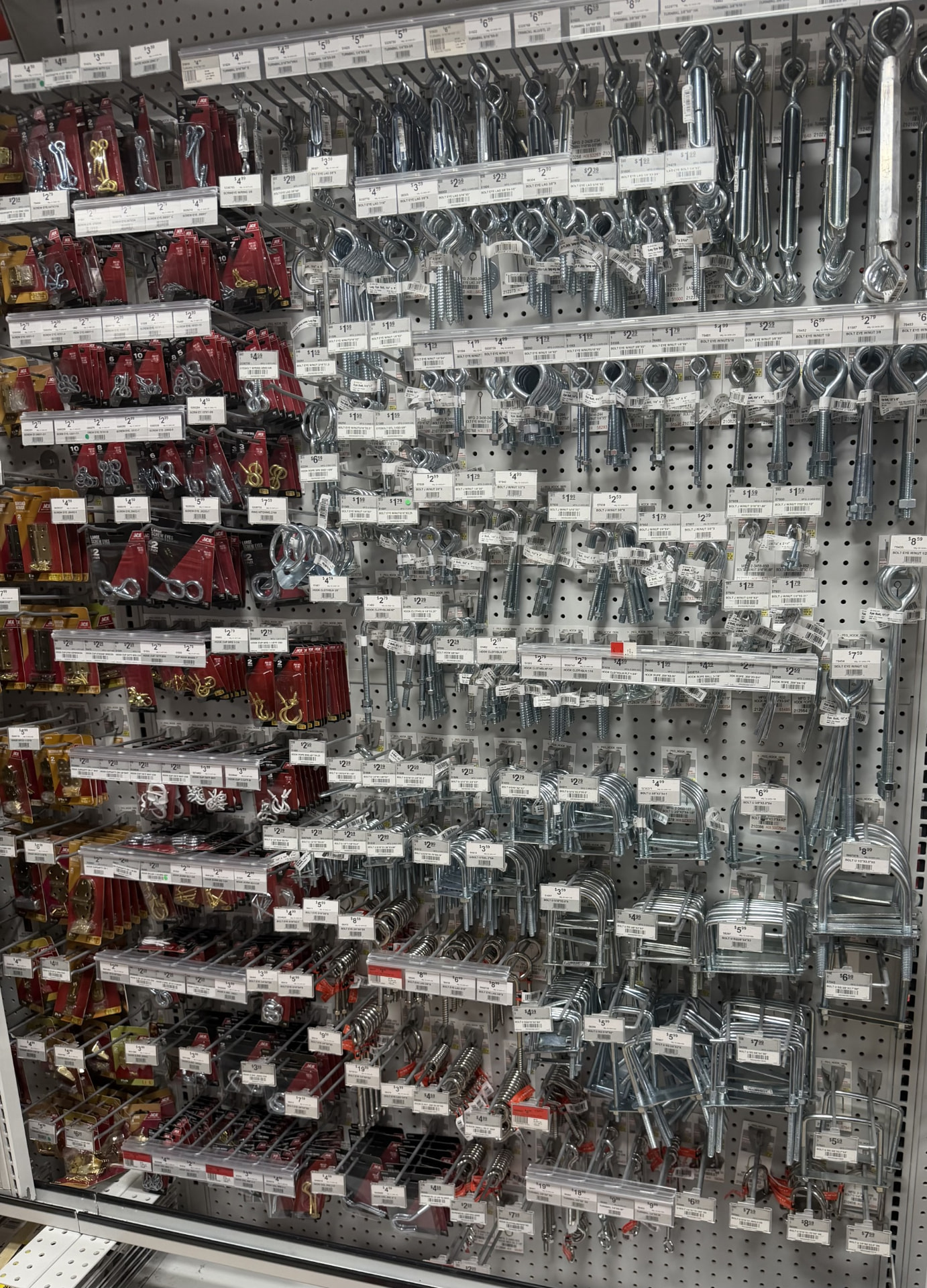 Pegboard wall of screw eyes, cup hooks, eye bolts, J-bolts, U-bolts and turnbuckles