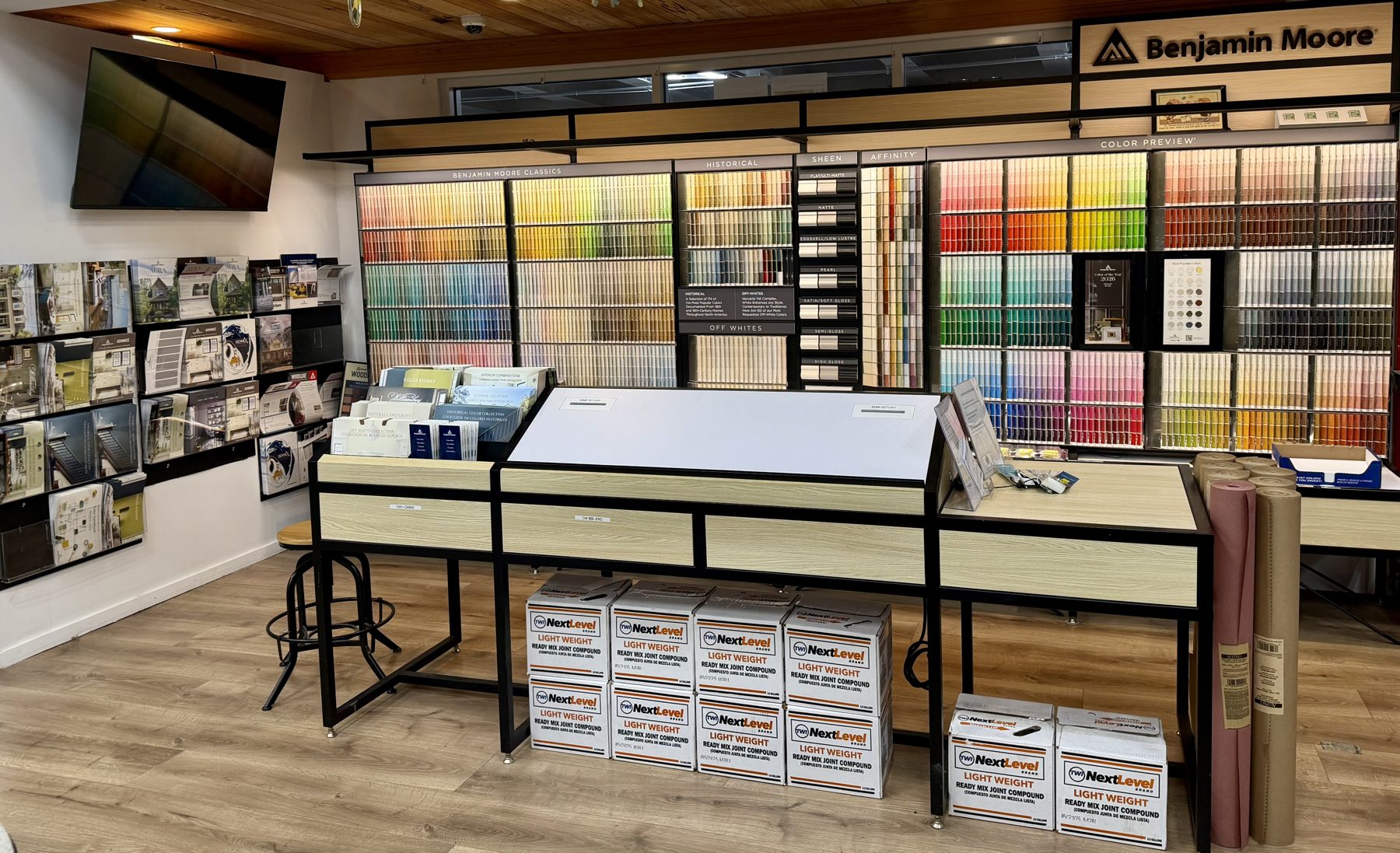 Benjamin Moore paint swatch display wall and consultation desk with boxes of Next Level lightweight joint compound underneath at Hessler Paint & Hardware in Delray Beach, Florida.