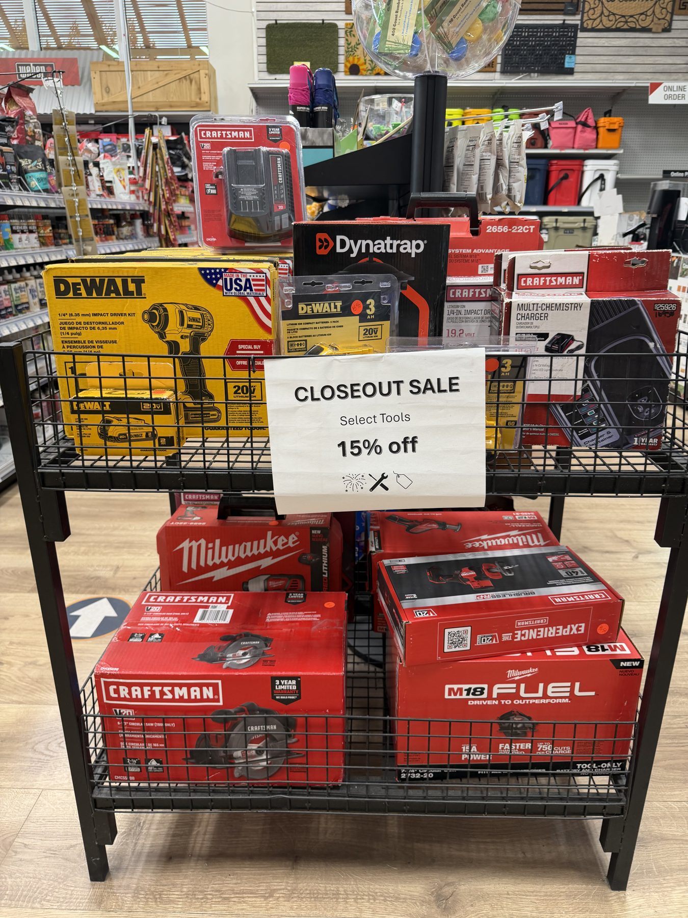 Closeout sale display rack featuring discounted DeWalt 20V MAX impact drivers, Milwaukee M18 FUEL power tools, and Craftsman cordless tools at Hessler Paint & Hardware in Delray Beach, Florida.