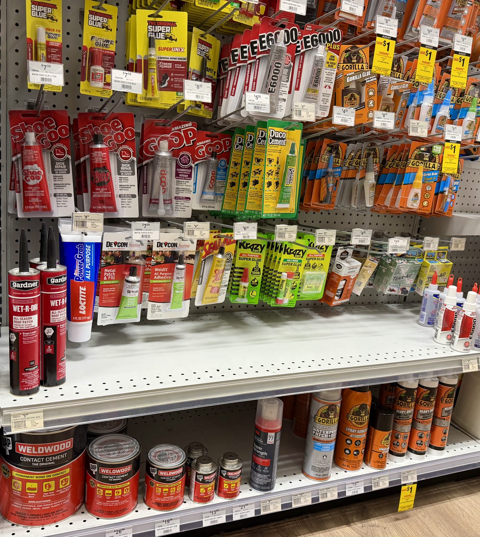 Aisle display of specialty adhesives, glues, and sealants including Gorilla Glue, E6000, Krazy Glue, Shoe Goo, DAP Weldwood Contact Cement, and Loctite at Hessler Paint & Hardware in Delray Beach, Florida.
