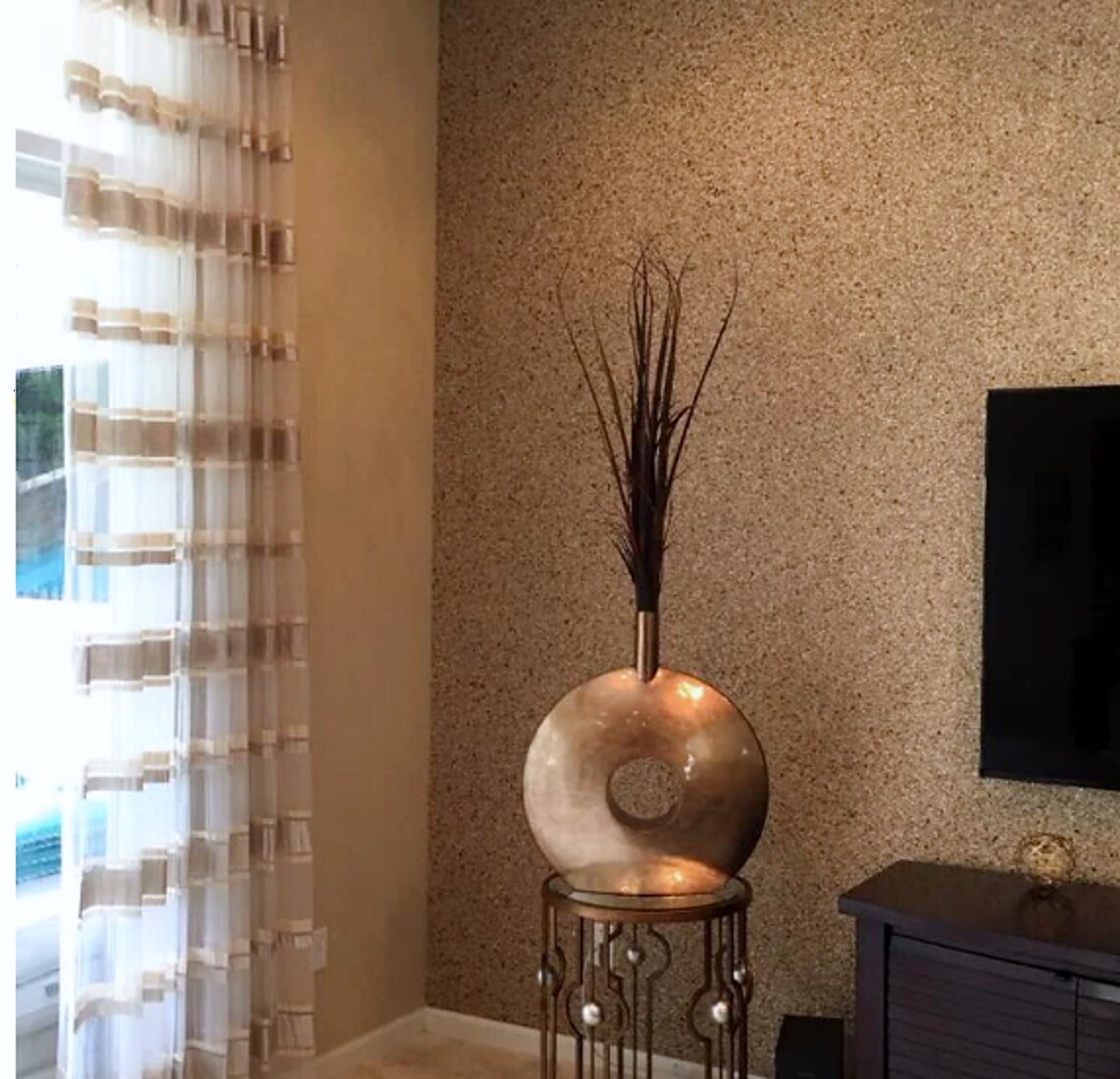 Banded sheer panel beside a textured grasscloth wall in a living room