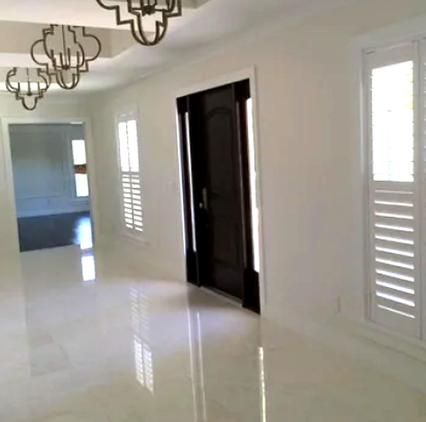 White plantation shutters on a foyer window and sidelight beside a dark mahogany front door