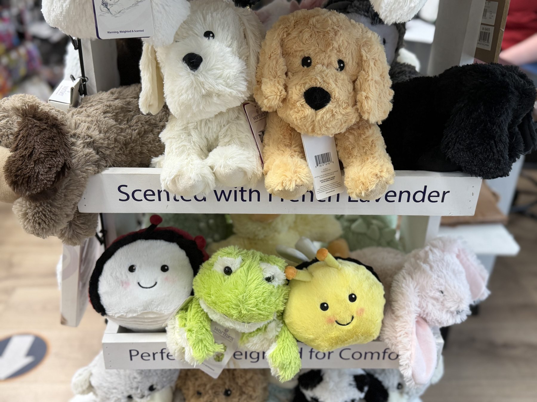 Display of Warmies lavender-scented weighted plush stuffed animals including puppy dogs, frogs, and bees at Hessler Paint & Hardware in Delray Beach, Florida.