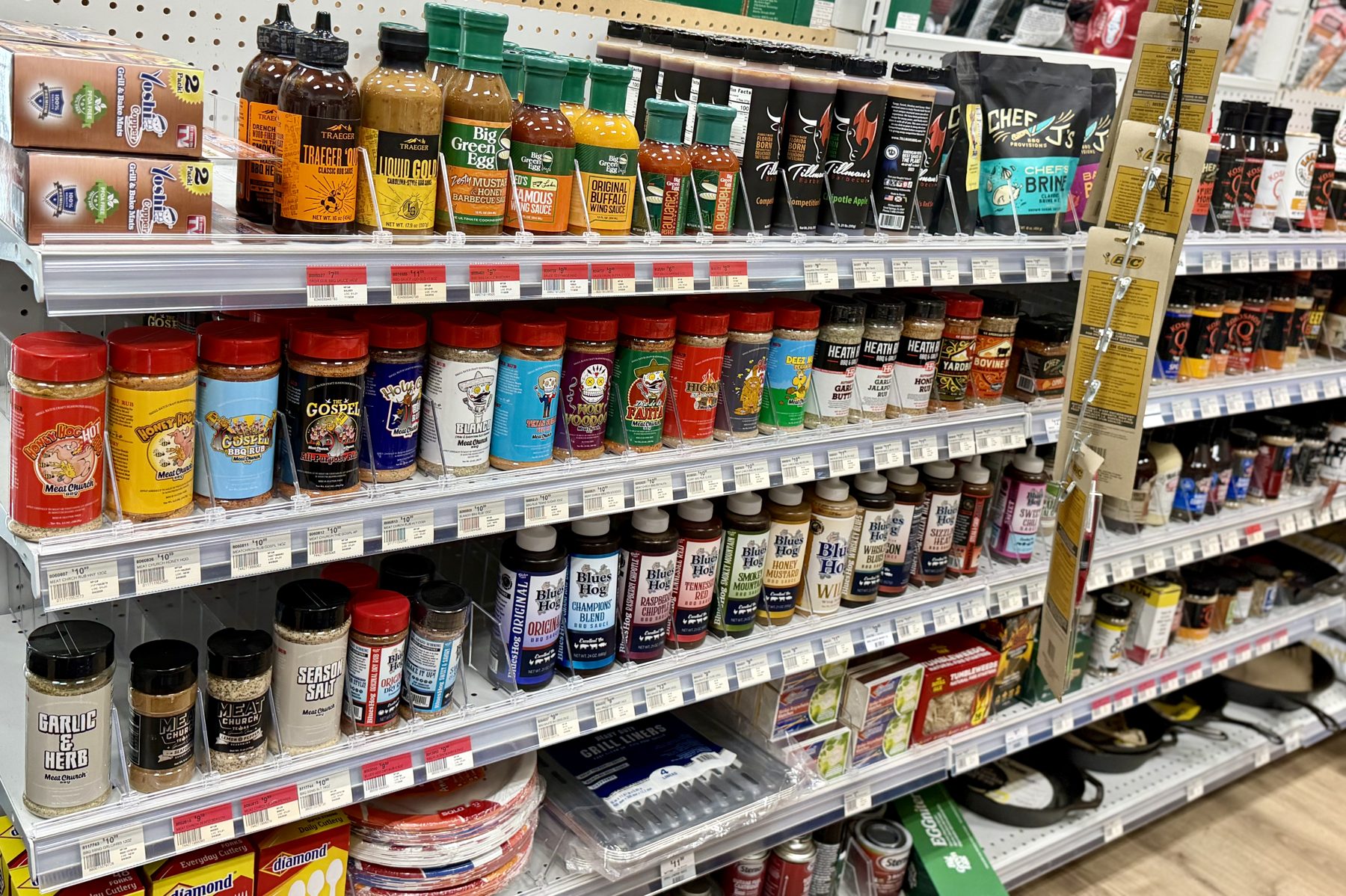 Shelves stocked with grilling rubs, seasonings, and sauces from Meat Church, Traeger, Big Green Egg, and Blues Hog at Hessler Paint & Hardware in Delray Beach, Florida.
