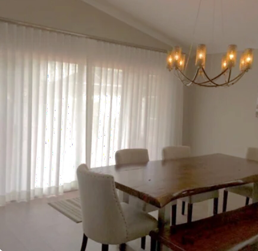 Floor-to-ceiling semi-sheer ripplefold drapery across a wide dining room slider
