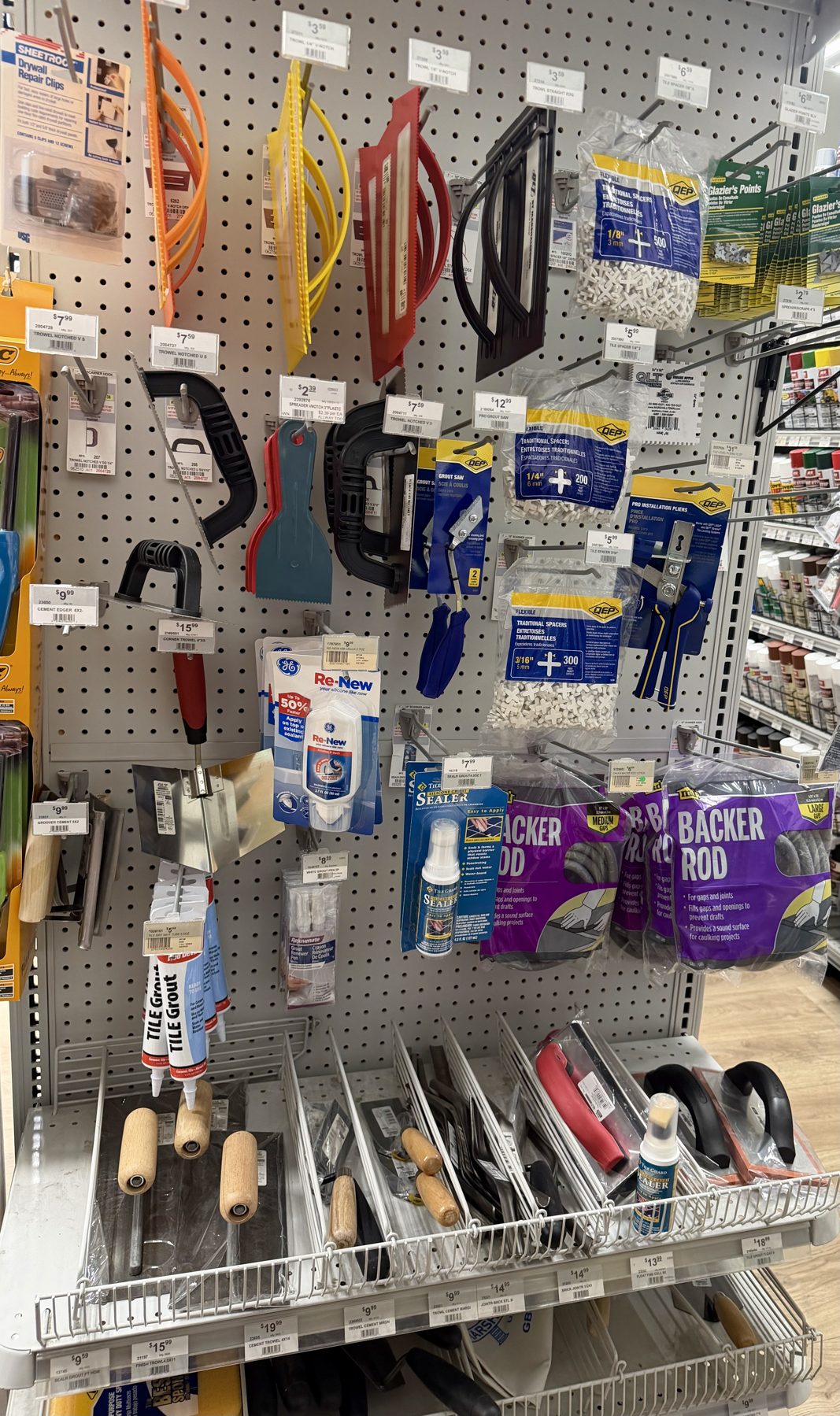 Pegboard display of tile tools including QEP tile spacers, backer rod, tile grout tubes, float trowels, and grout sealer at Hessler Paint & Hardware in Delray Beach, Florida.