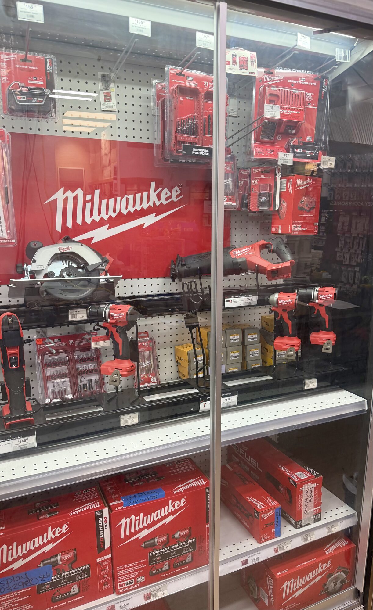 A glass display case featuring Milwaukee power tools including a circular saw, reciprocating saw, and drills at Hessler Paint & Hardware in Delray Beach, Florida.