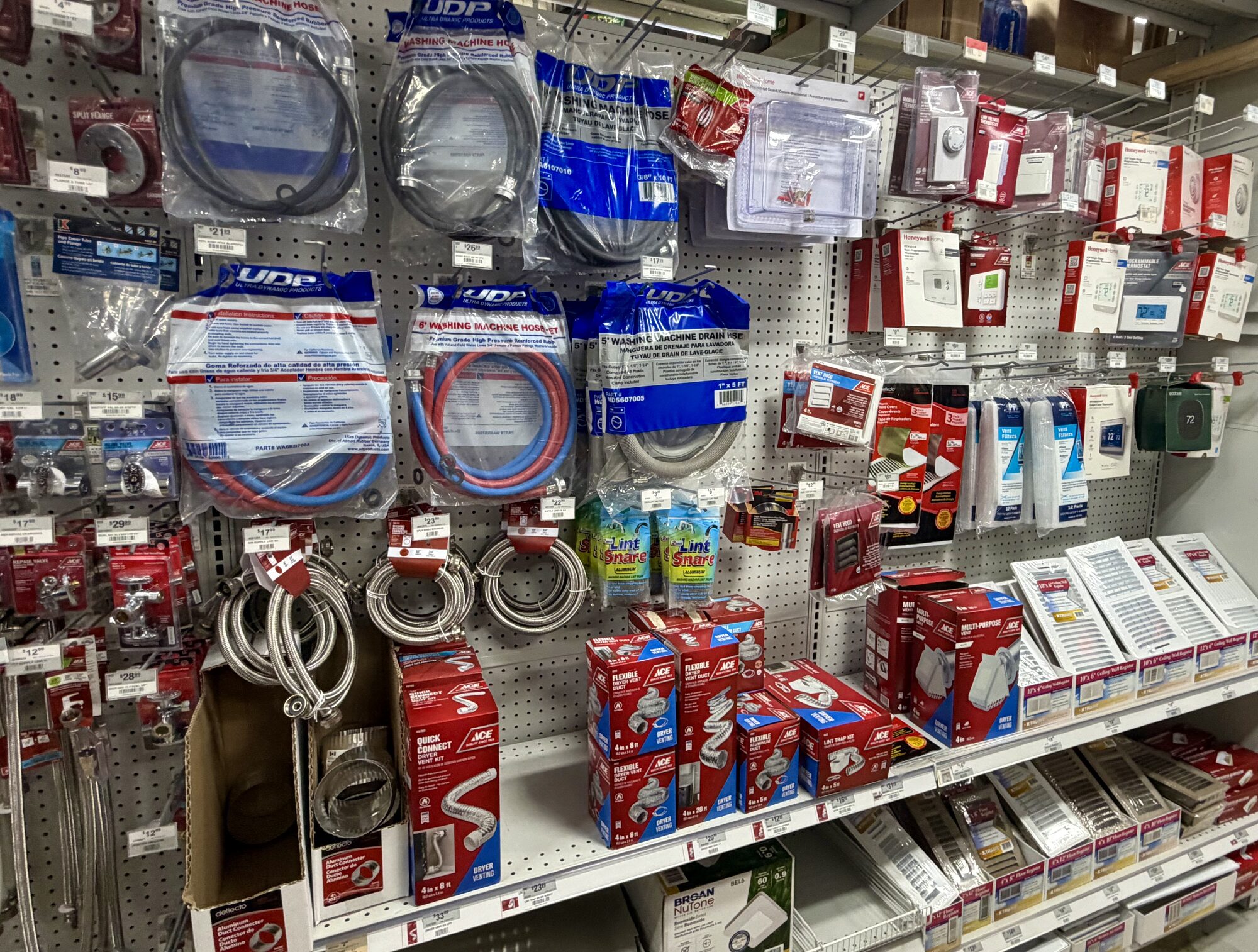 Shelves of UDP washing machine hoses, Ace dryer vent kits, and lint snares at Hessler Paint & Hardware in Delray Beach, Florida.