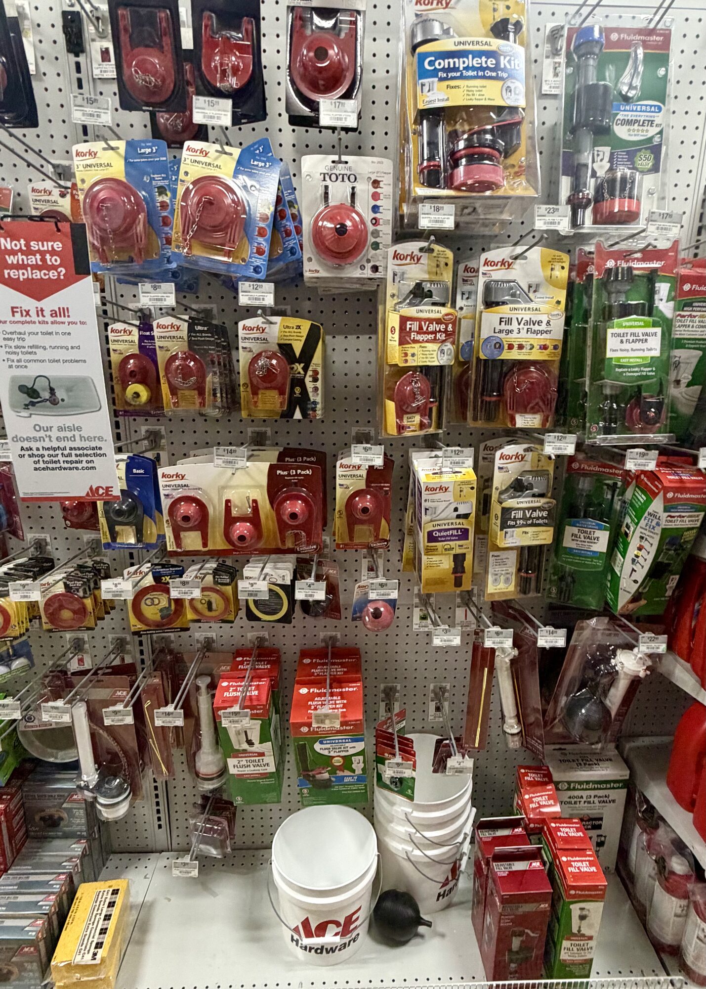 Toilet repair parts including Korky flappers, Fluidmaster fill valves, Toto flappers, and Ace Hardware buckets at Hessler Paint & Hardware in Delray Beach, Florida.