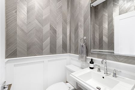 Powder room with silver-grey herringbone specialty wallcovering above white wainscoting