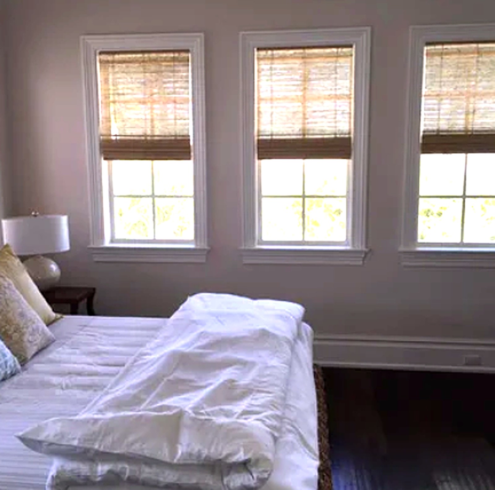 Three bedroom windows fitted with natural woven wood shades in a soft bamboo tone