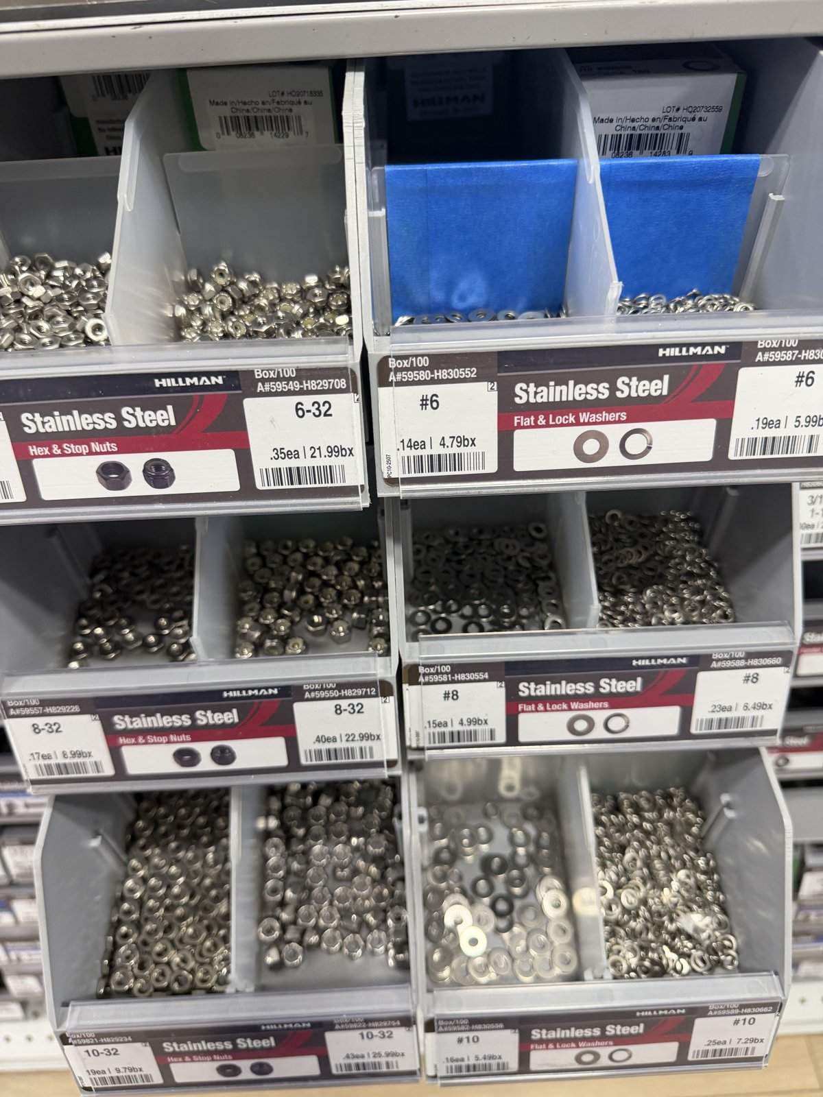 Stainless steel hex nuts, stop nuts, flat washers and lock washers in labeled Hillman bins