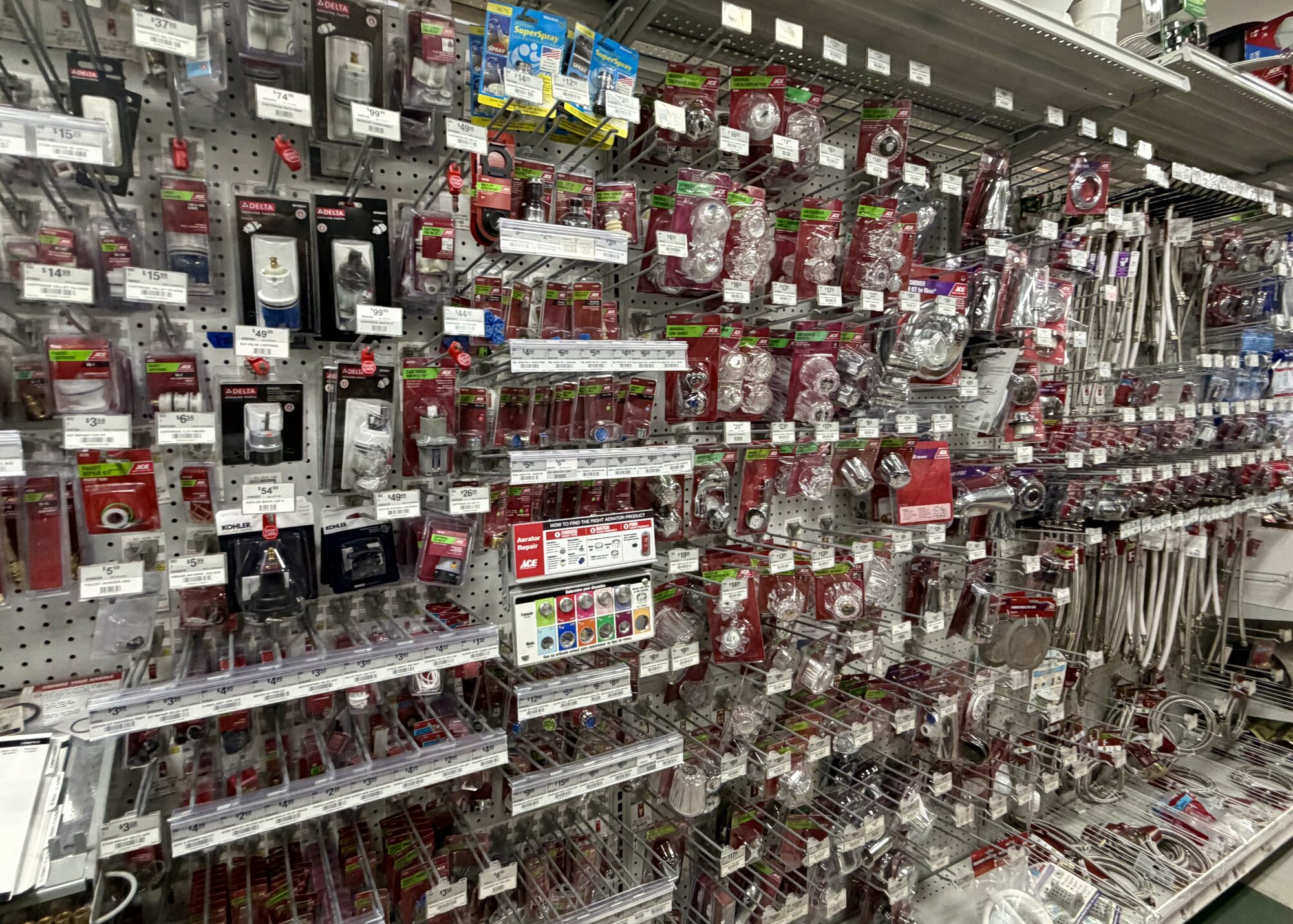 Shelves of Delta, Kohler, and Ace plumbing repair parts including faucet handles and supply lines at Hessler Paint & Hardware in Delray Beach, Florida.