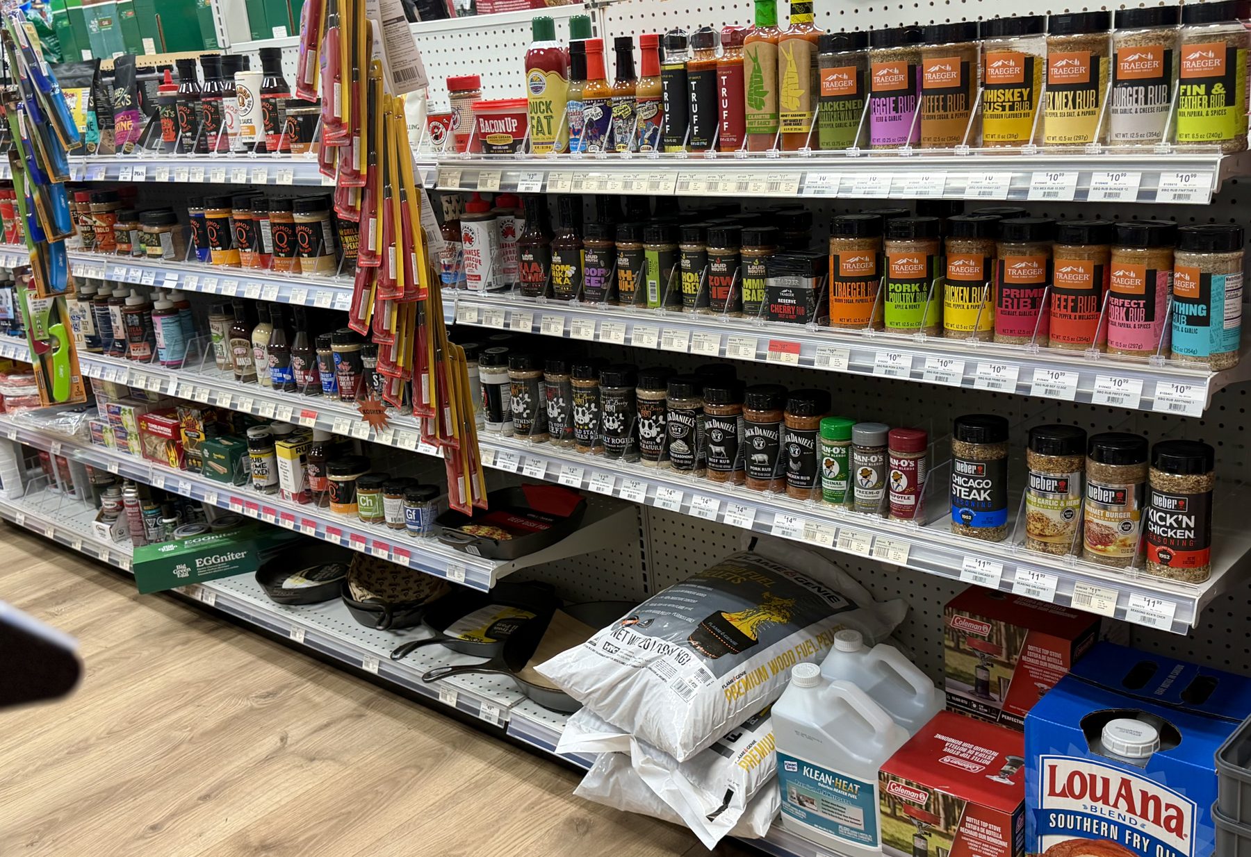 Shelves filled with Traeger rubs, Weber seasonings, TRUFF hot sauces, Dan-O's spices, cast iron skillets, and grilling fuel pellets at Hessler Paint & Hardware in Delray Beach, Florida.