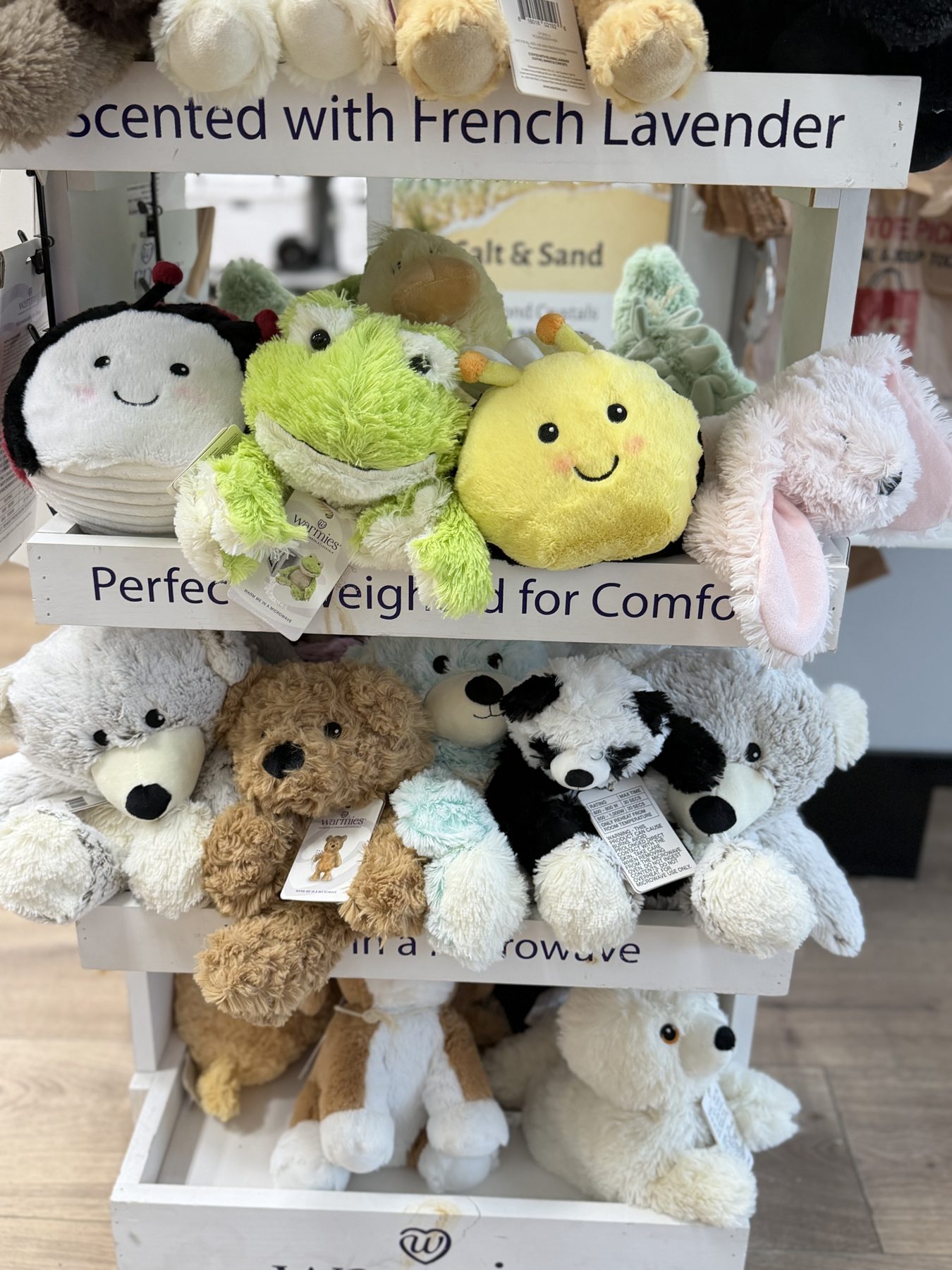 Warmies microwavable French lavender scented plush stuffed animals featuring frogs, bees, bunnies, and teddy bears on display at Hessler Paint & Hardware in Delray Beach, Florida.