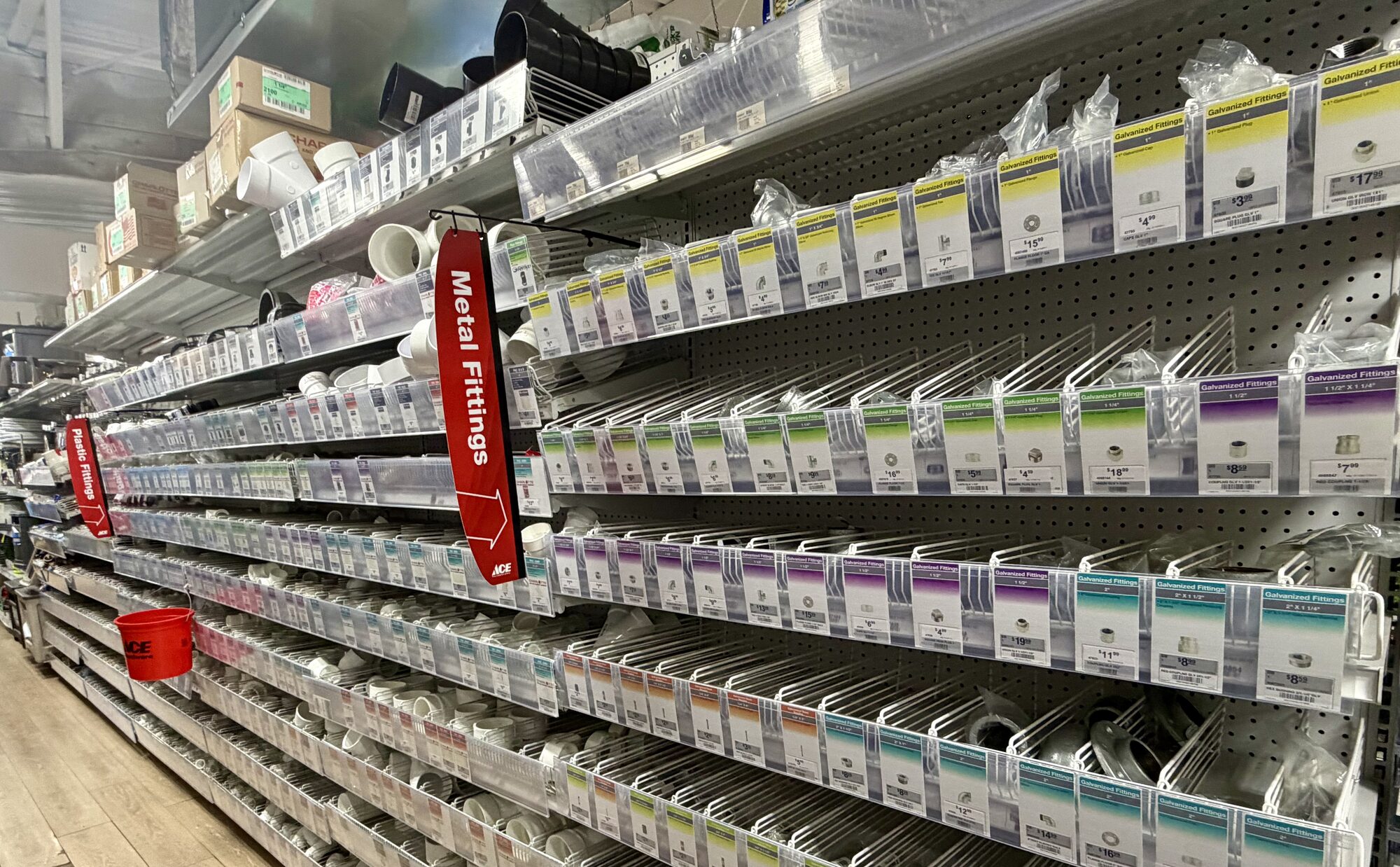 Shelves stocked with Ace branded metal fittings, galvanized fittings, and PVC plastic fittings at Hessler Paint & Hardware in Delray Beach, Florida.