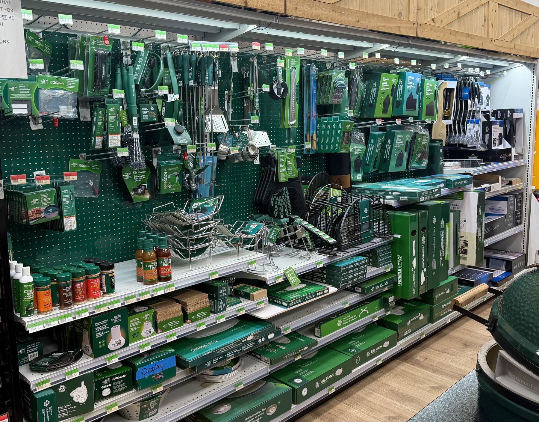 Wall display of official Big Green Egg accessories, grilling tools, sauces, seasonings, and egg mates at Hessler Paint & Hardware in Delray Beach, Florida.