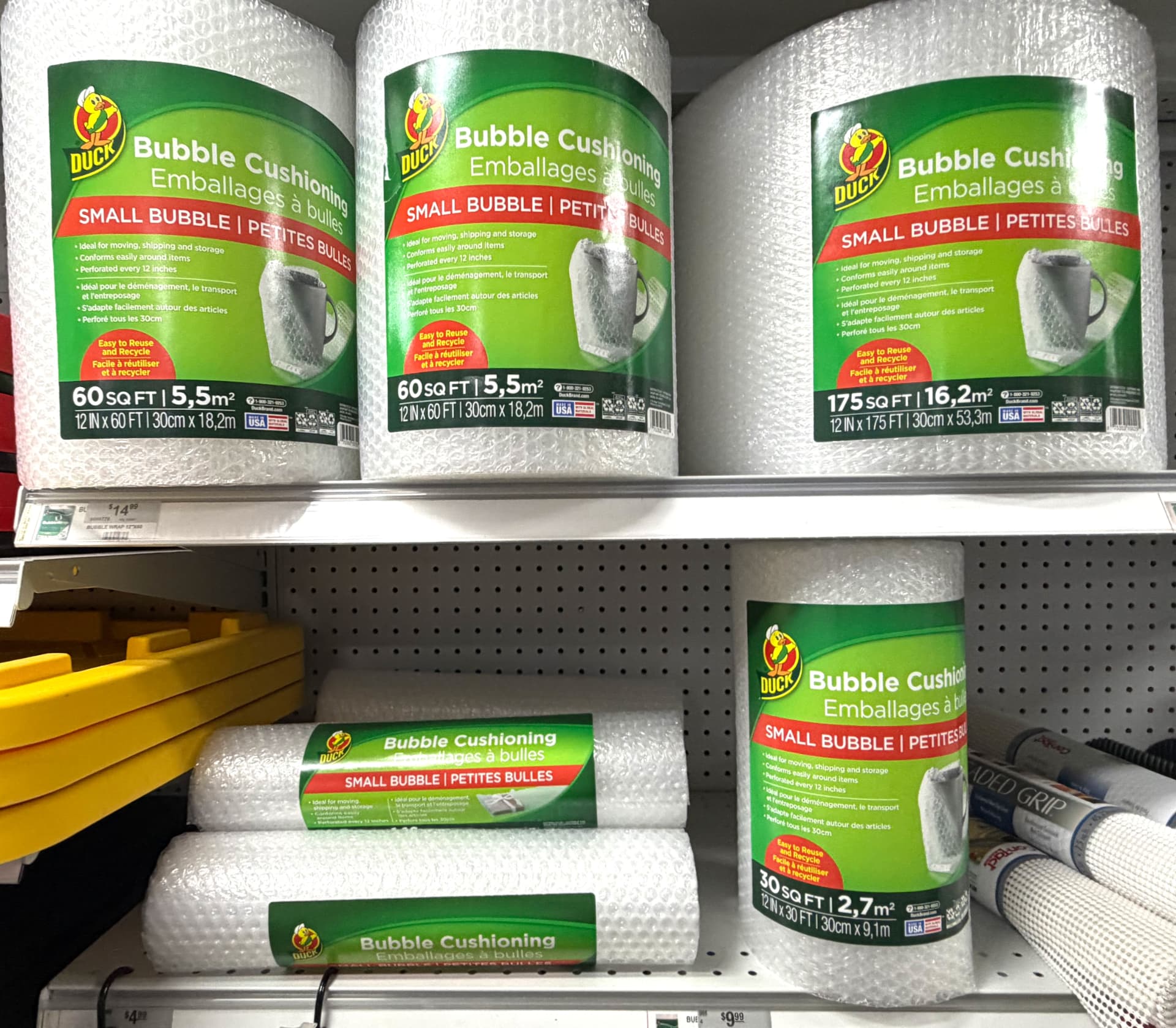 Rolls of Duck brand small bubble cushioning wrap in 30, 60 and 175 square foot sizes on a store shelf