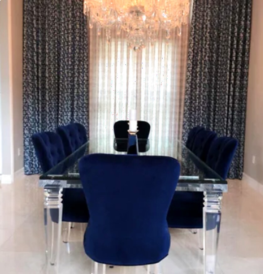 Patterned side panels and a sheer center panel framing a dining room window with a crystal chandelier