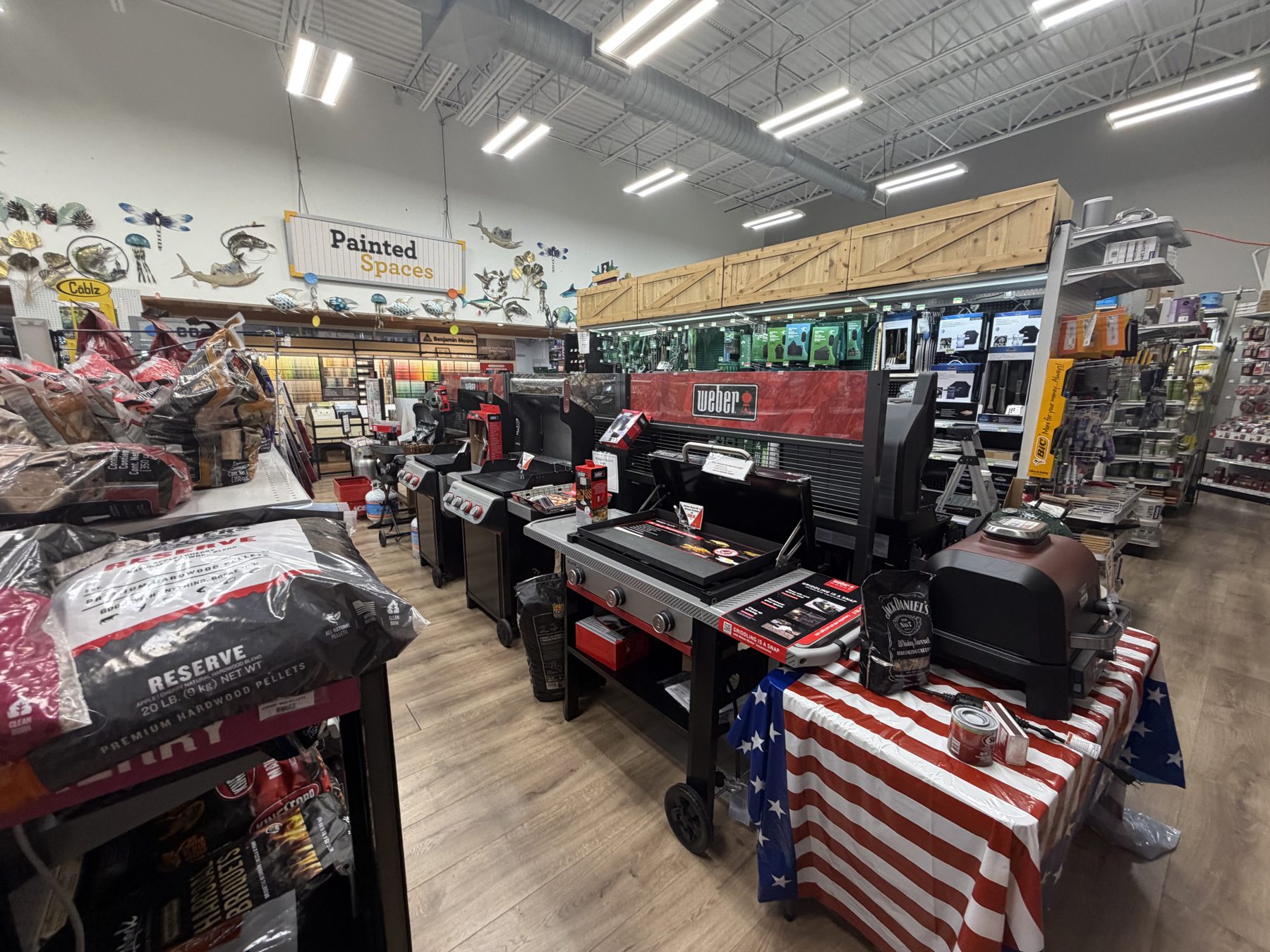 Weber gas grills, griddle stations, bags of hardwood pellets, and grilling accessories on display at Hessler Paint & Hardware in Delray Beach, Florida.