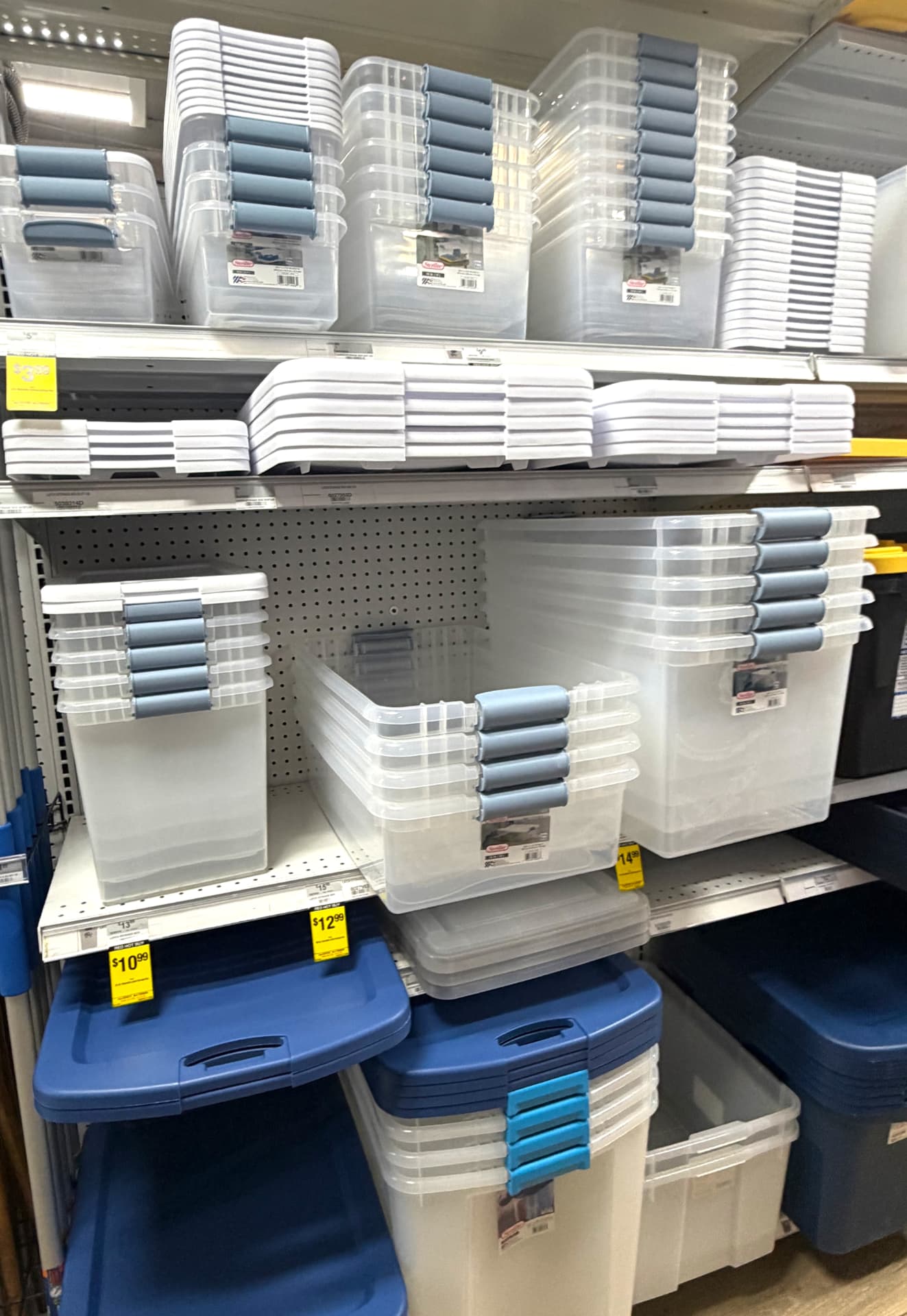 Shelves of clear Sterilite storage totes with blue latching lids in the storage aisle at Hessler Ace Hardware in Delray Beach