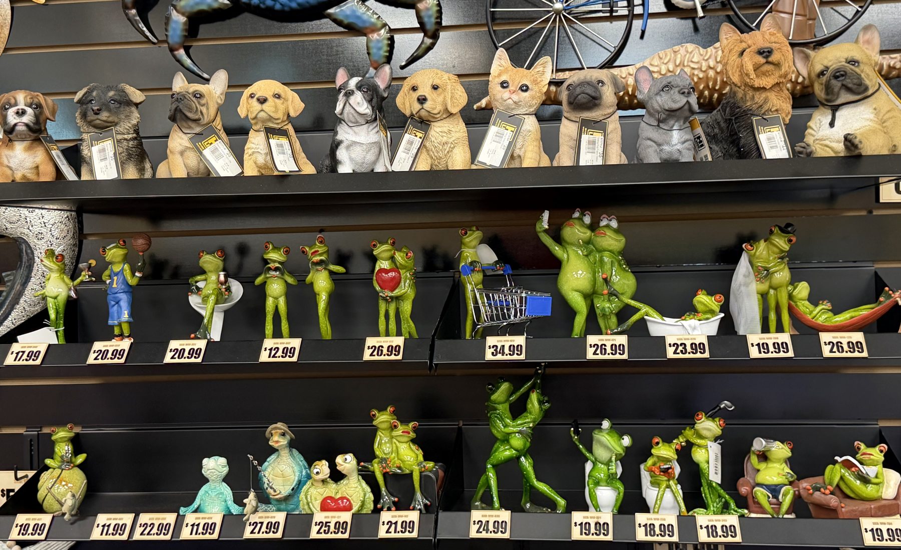 Display shelves filled with decorative dog and cat statues, whimsical frog figurines, and garden ornaments at Hessler Paint & Hardware in Delray Beach, Florida.