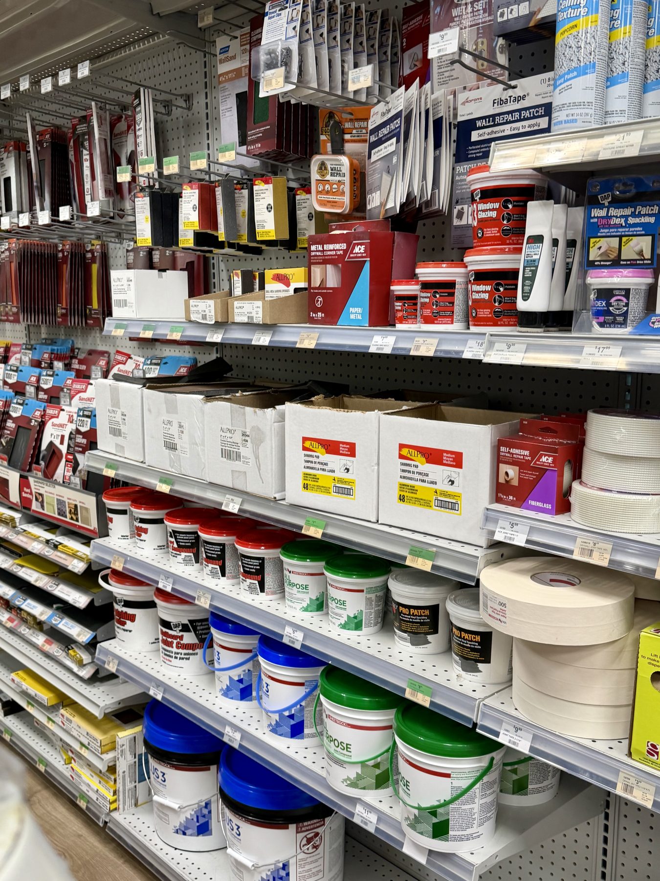 Shelves stocked with joint compound, DAP spackling, drywall tape, sandpaper, and wall repair patches at Hessler Paint & Hardware in Delray Beach, Florida.
