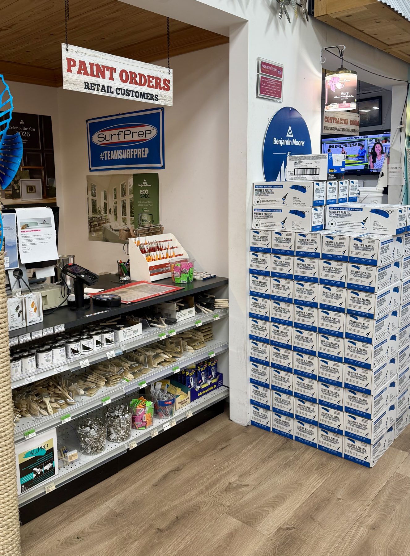 Retail paint order counter featuring SurfPrep signage, Benjamin Moore signage, paint brushes, and stacks of Painter's Plastic sheeting at Hessler Paint & Hardware in Delray Beach, Florida.