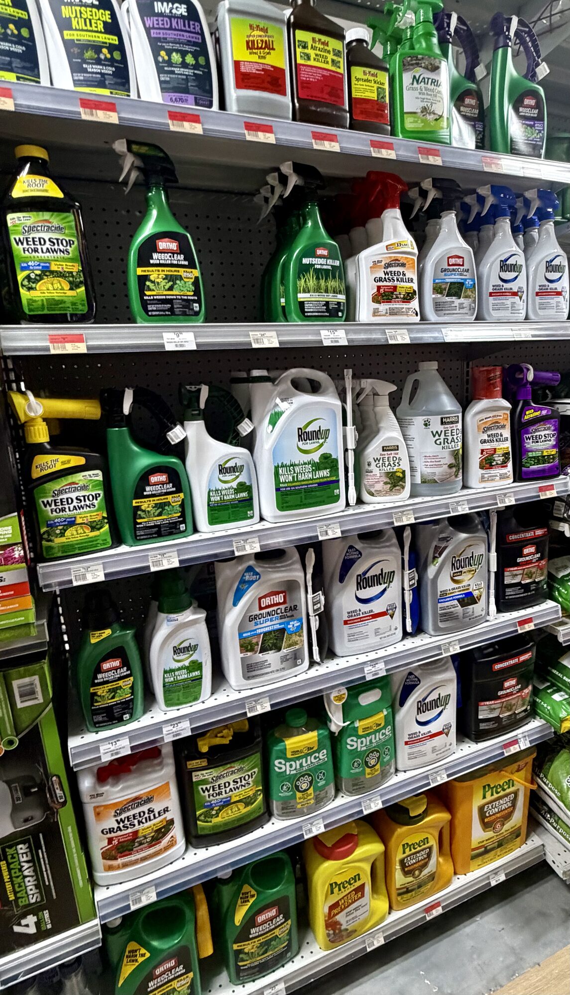 Shelves of weed control products including Ortho WeedClear, Roundup, Spectracide Weed Stop, and Preen at Hessler Paint & Hardware in Delray Beach, Florida.