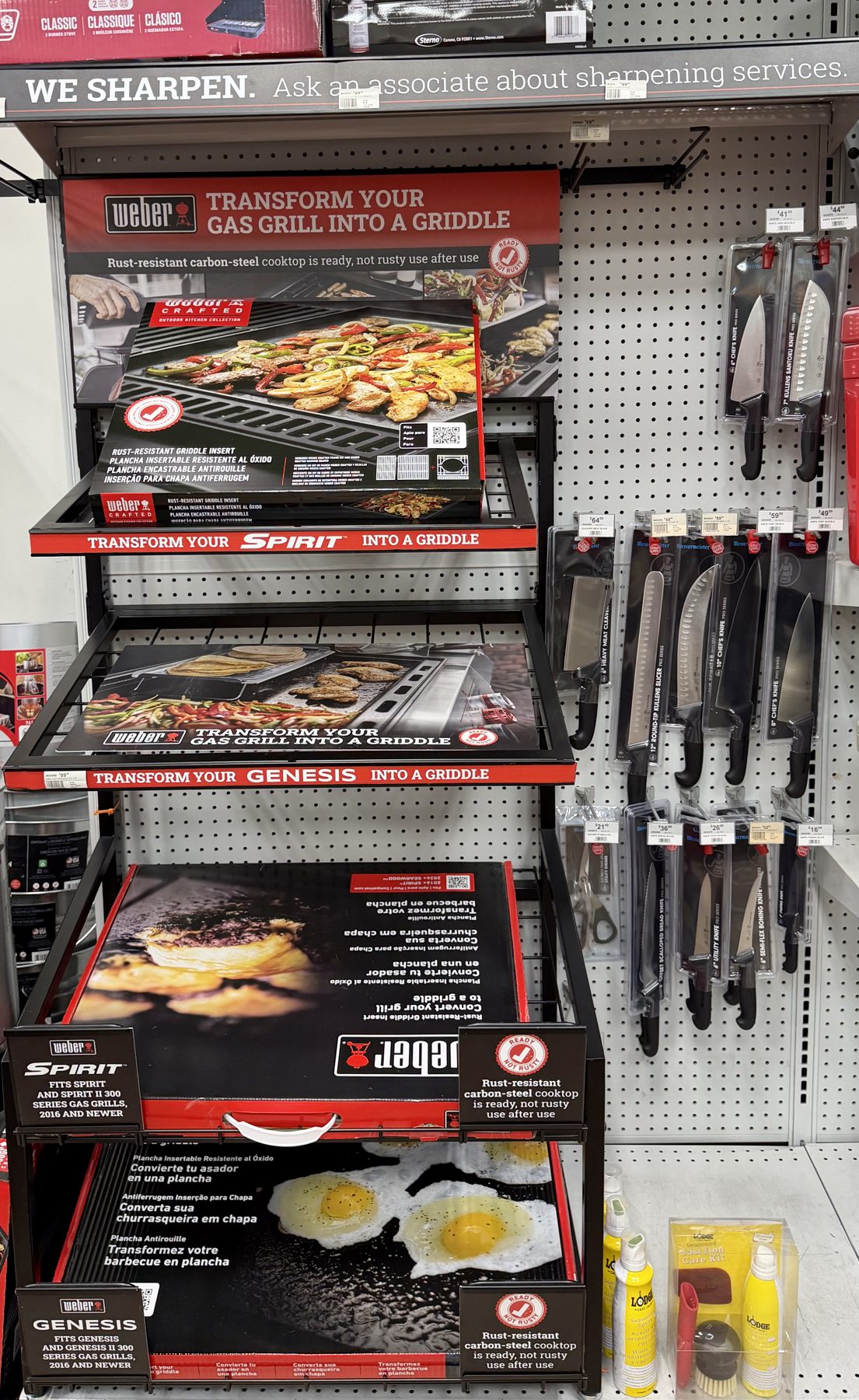 Weber Crafted gas grill griddle inserts for Spirit and Genesis grills displayed alongside barbecue knives and cutlery at Hessler Paint & Hardware in Delray Beach, Florida.