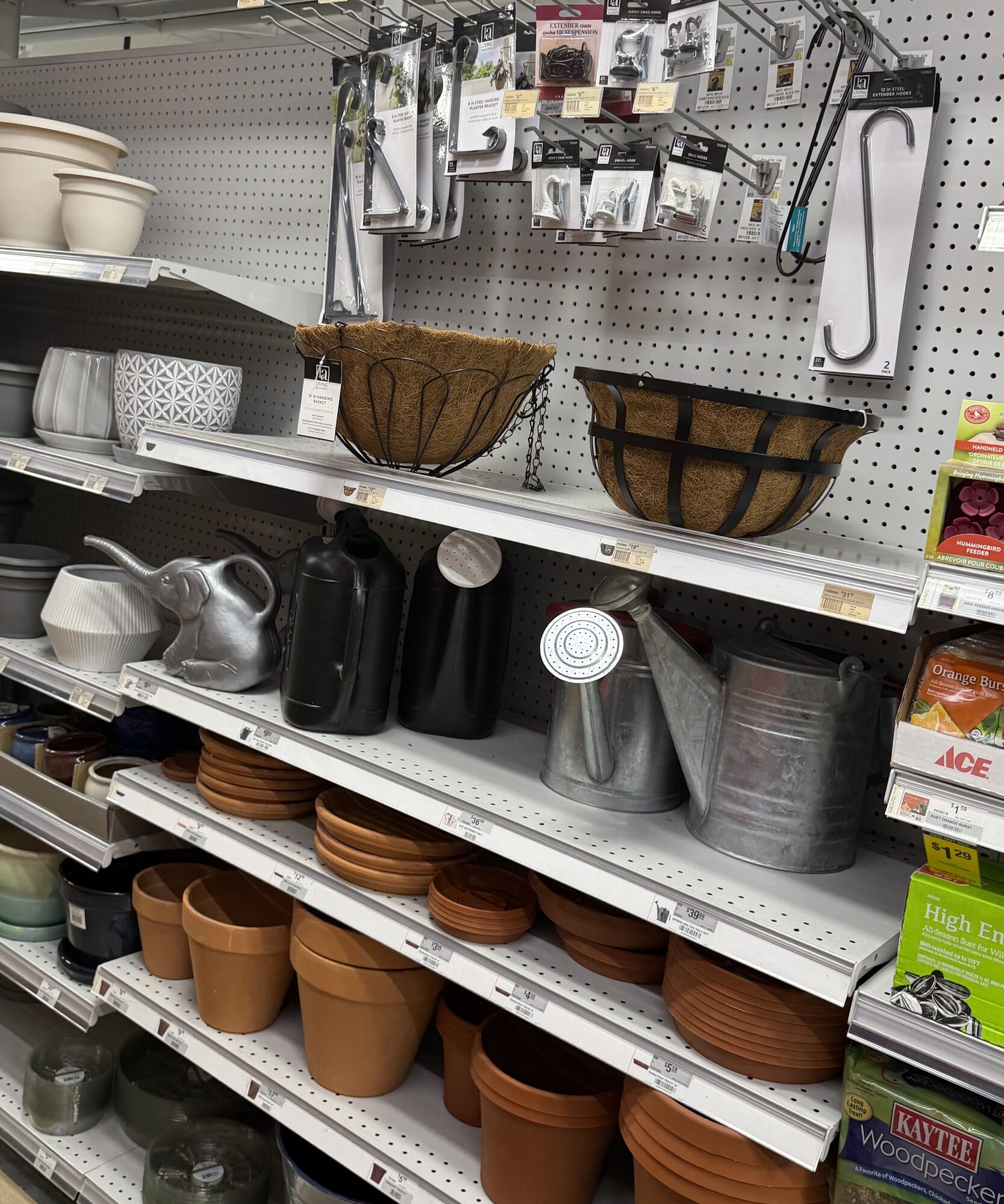 Shelves stocked with terracotta pots, watering cans, coco liner hanging baskets, and Ace brand bird seed at Hessler Paint & Hardware in Delray Beach, Florida.