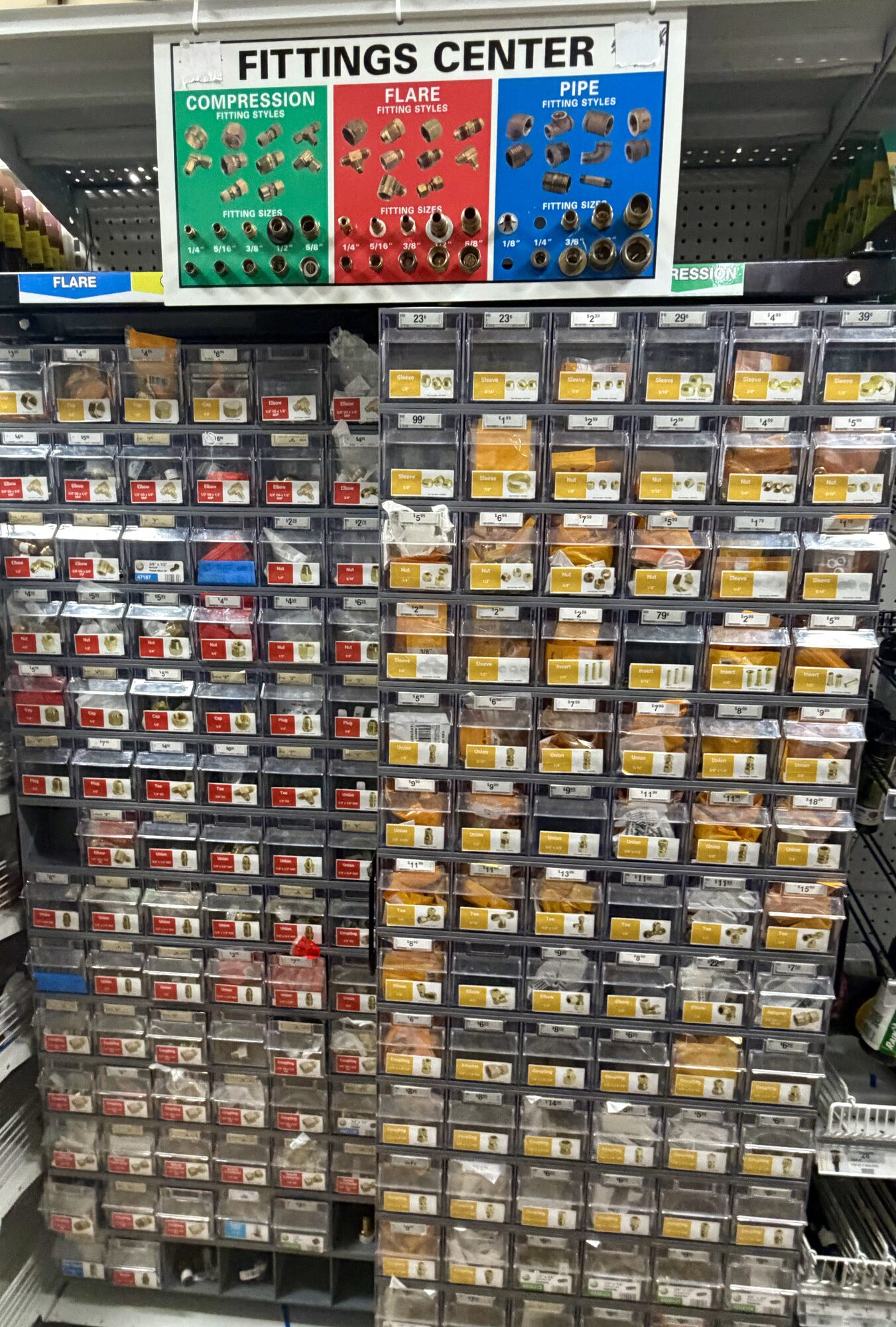 A Fittings Center display featuring compression, flare, and pipe fitting styles in organized bins at Hessler Paint & Hardware in Delray Beach, Florida.