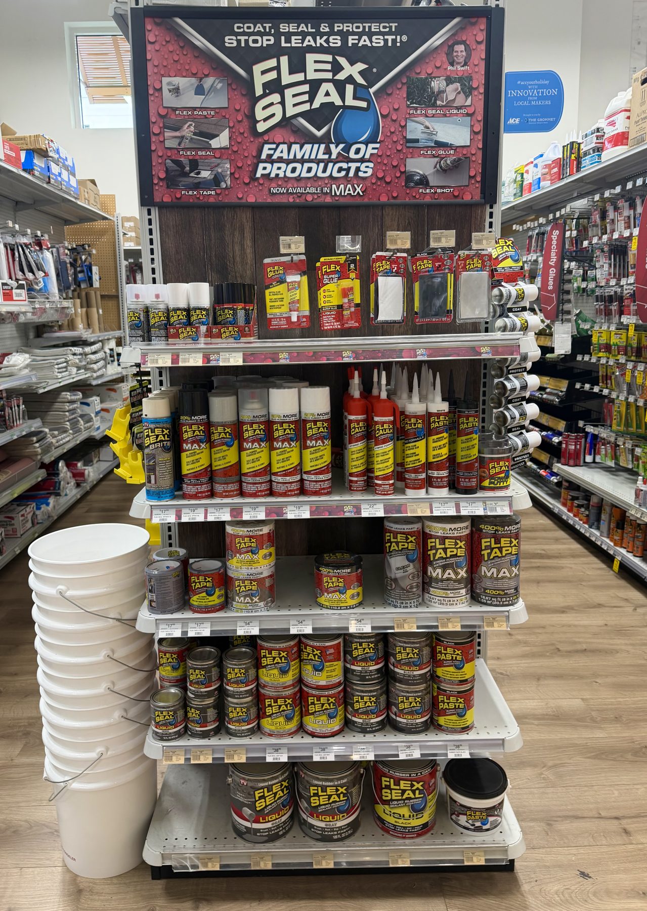 Endcap display featuring Flex Seal spray cans, Flex Tape MAX, Flex Glue caulk tubes, and Flex Seal Liquid rubberized coating containers at Hessler Paint & Hardware in Delray Beach, Florida.