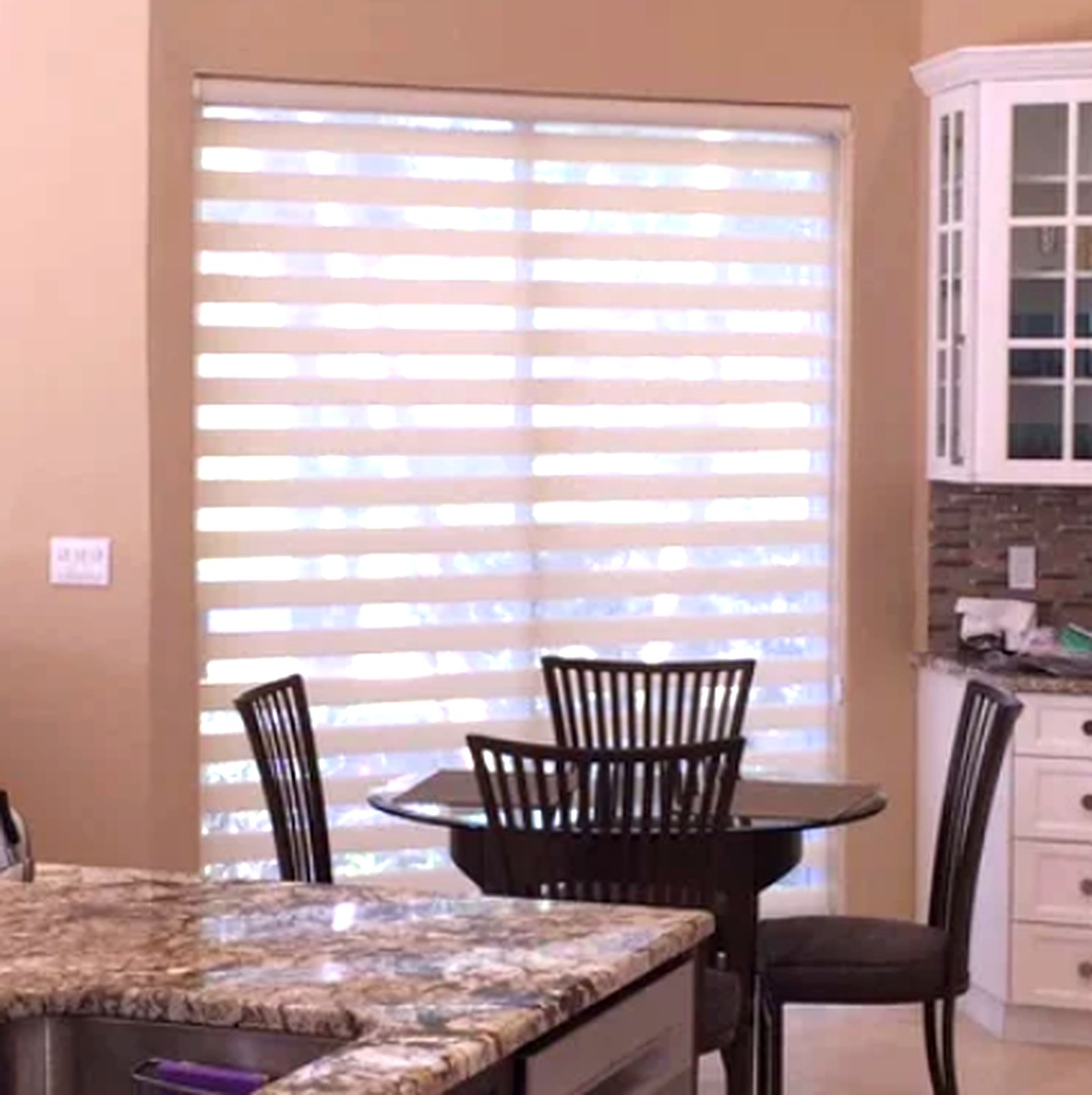 Allure banded shade covering a wide kitchen slider, sheer and solid bands filtering daylight over a dining table