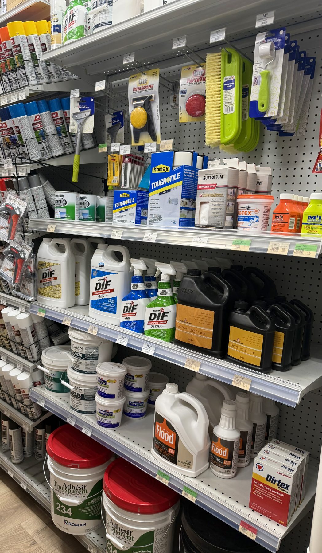 Shelves stocked with wallpaper removers and surface prep tools including Zinsser DIF, Flood Floetrol, Homax Tough Tile, and Roman adhesives at Hessler Paint & Hardware in Delray Beach, Florida.